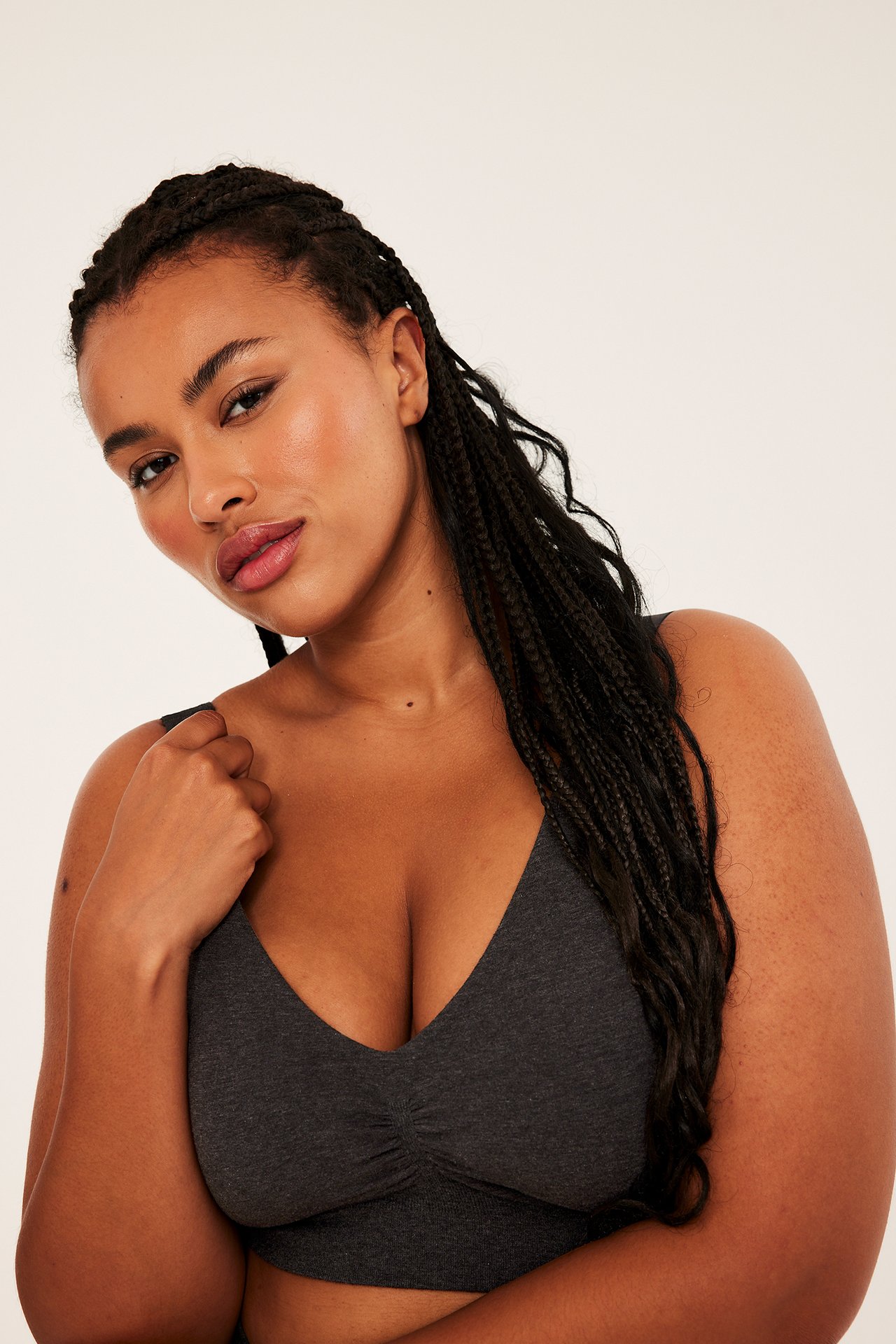 Framsida av en mörkgrå mjuk V-ringad bralette buren av en kvinnlig modell.