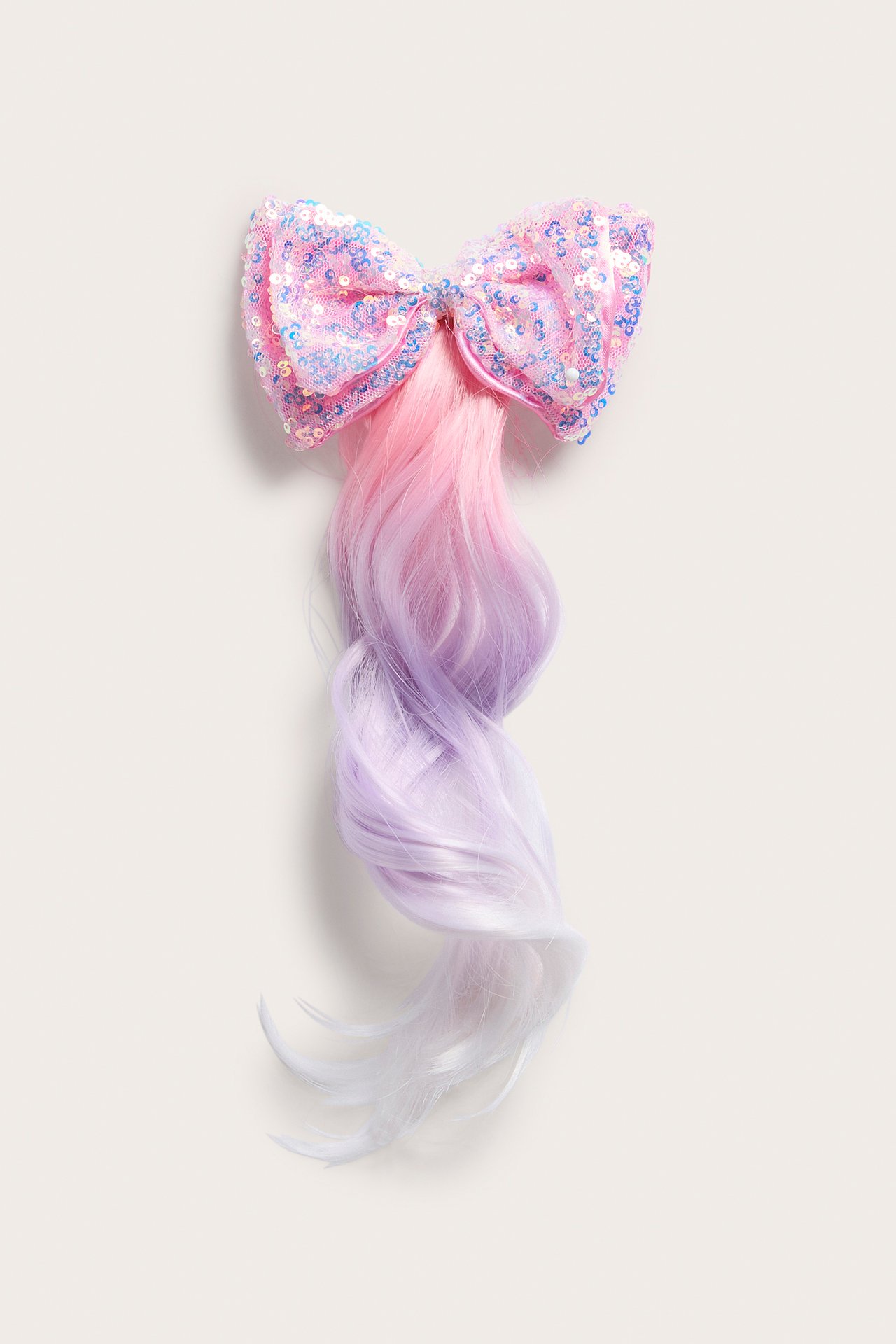 Front view av en rosa paljett hårspenne med ombre rosa til lilla bølgete hårextension.