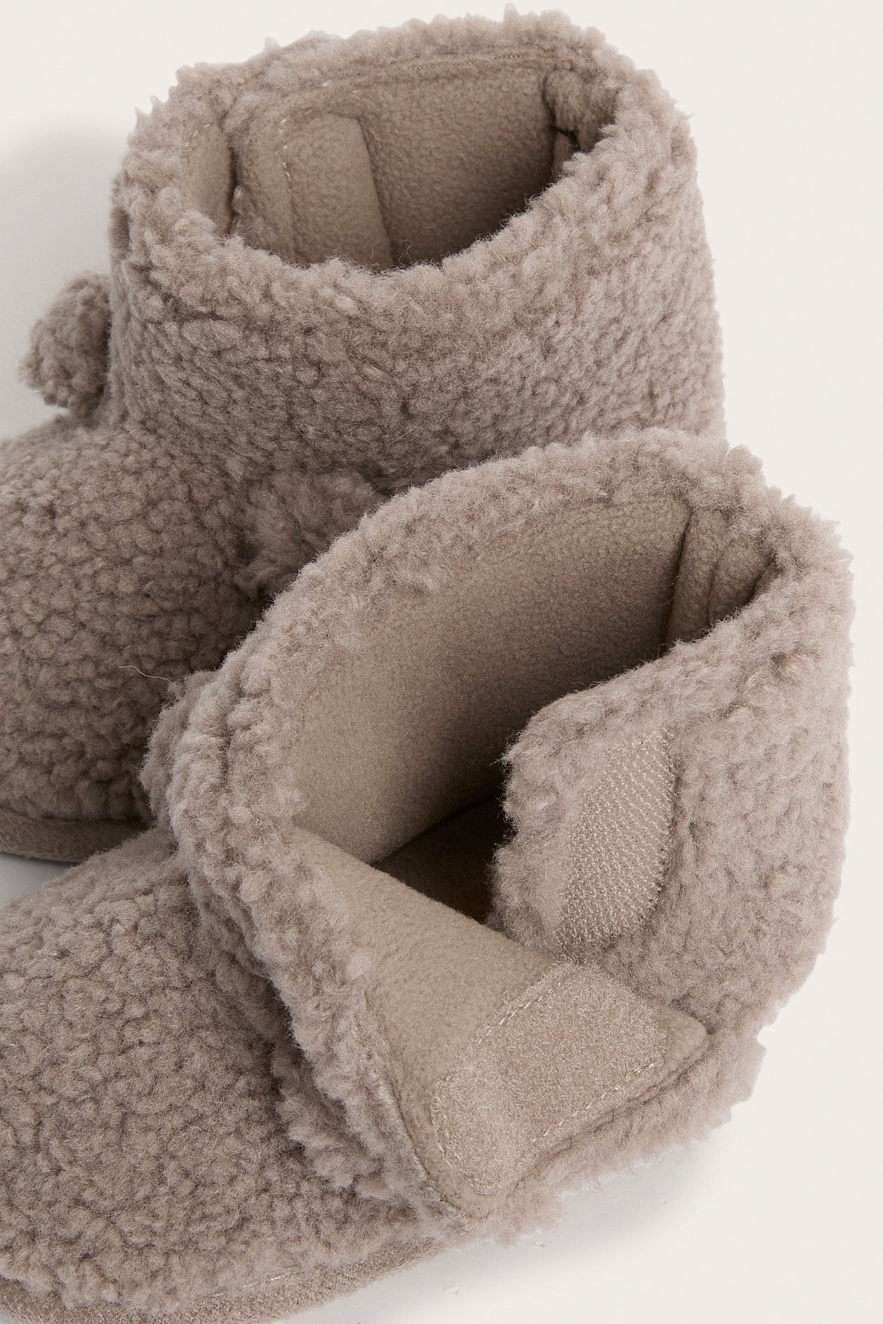 Närbild på ett par ljusbruna fluffiga babytofflor med kardborreknäppning.