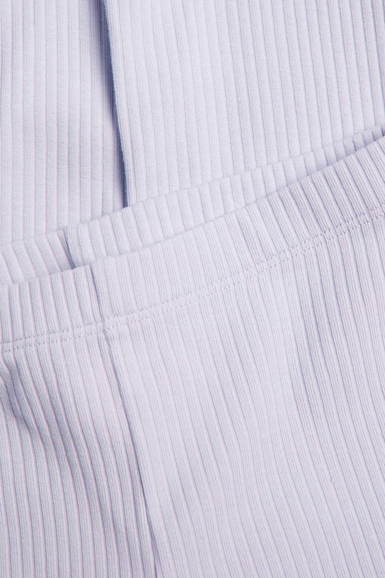 Närbild på ljuslila ribbade trikåleggings med elastisk midja.