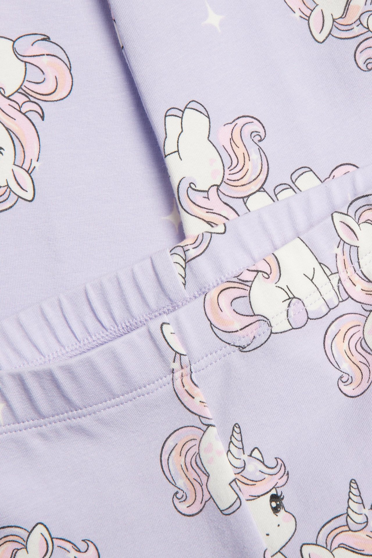 Zbliżenie jasnofioletowych bawełnianych legginsów z elastyczną talią i wzorem w jednorożce.