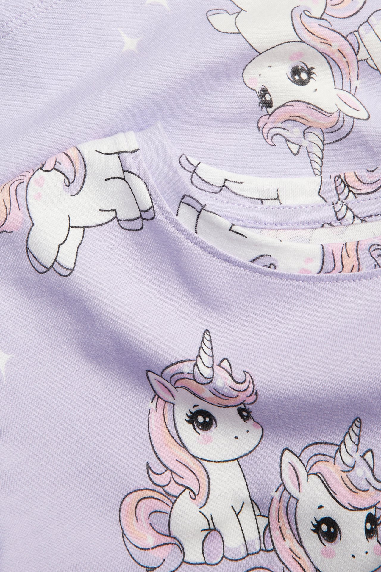 Närbild av en barns ljuslila bomullstopp med gulligt enhörnings- och stjärnmönster.