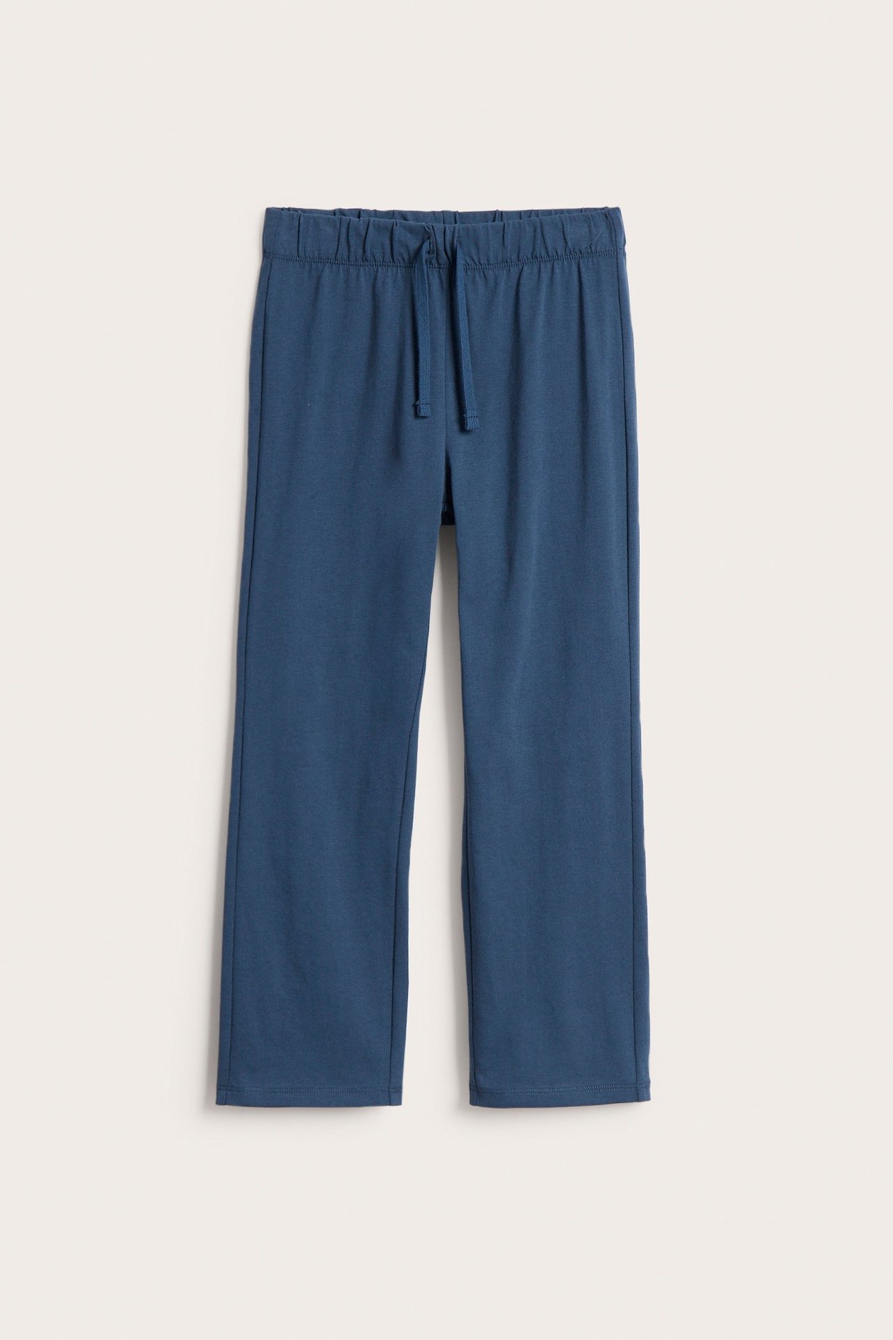 Widok z przodu niebieskich, bawełnianych spodni dresowych z prostymi nogawkami i sznurkiem.