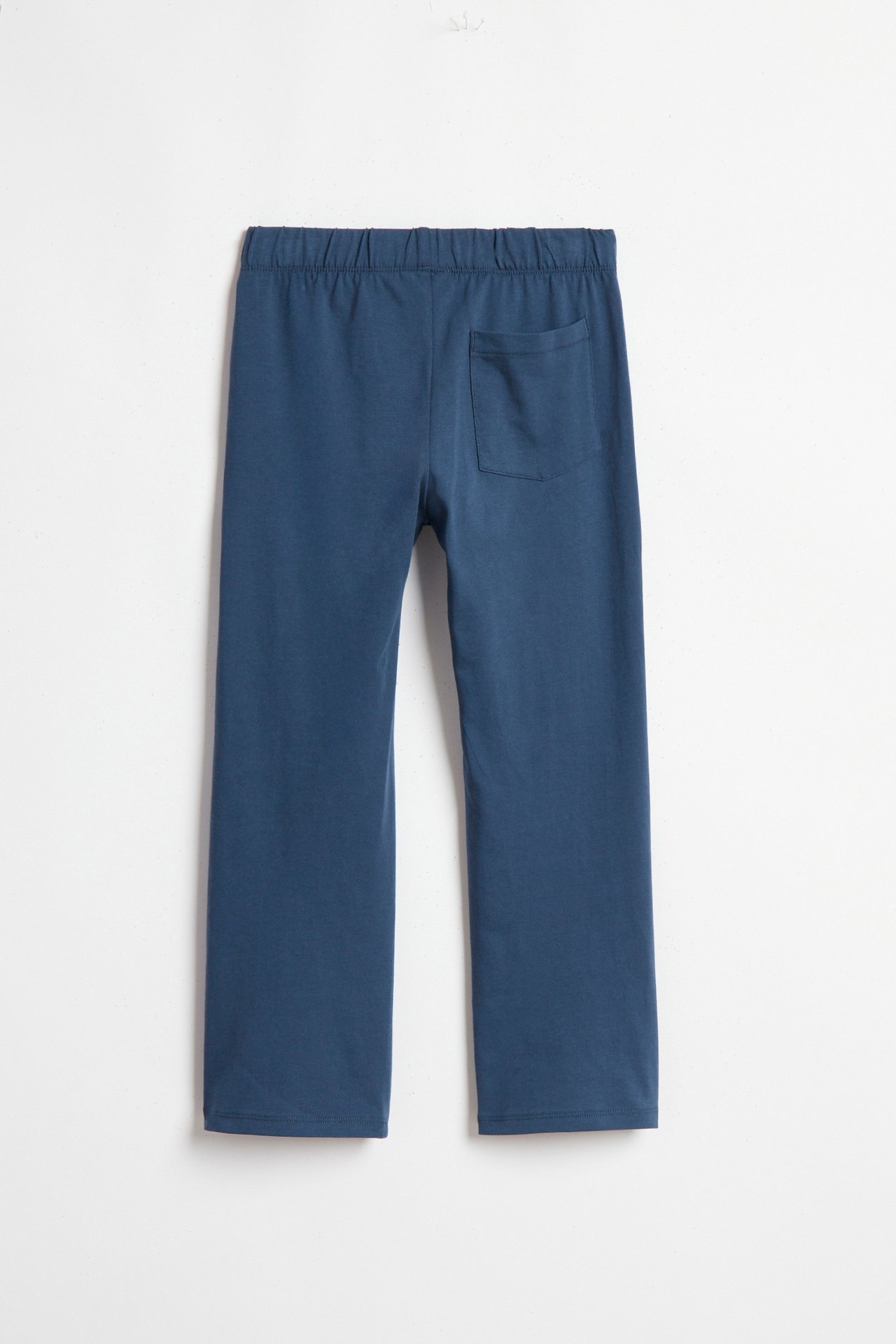 Takanäkymä: Siniset suoralahkeiset collegehousut joustovyötäröllä ja yhdellä takataskulla.