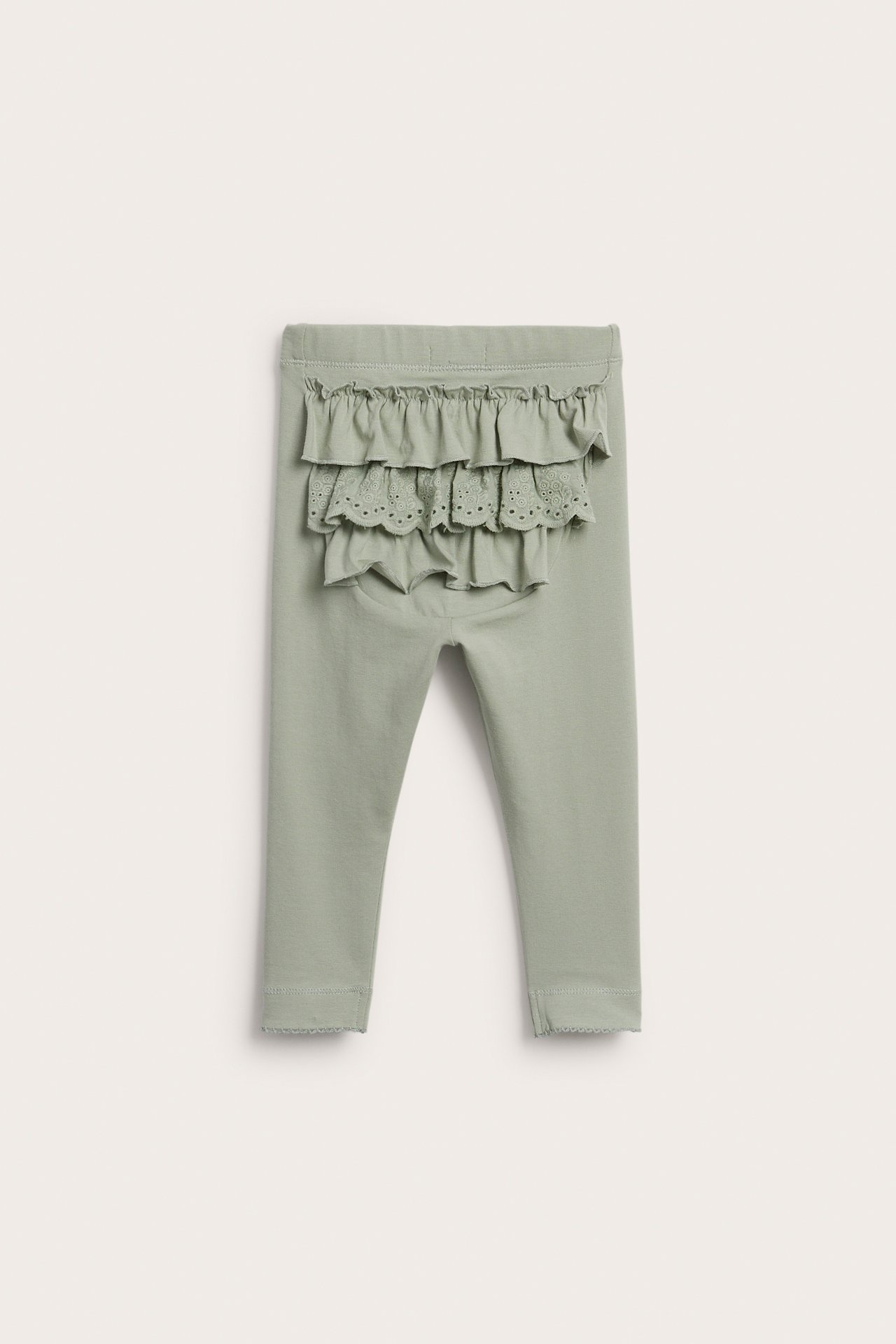 Bakifrån: Gröna baby-bomullsleggings med elastisk midja, volanger och spetsdetaljer bak.