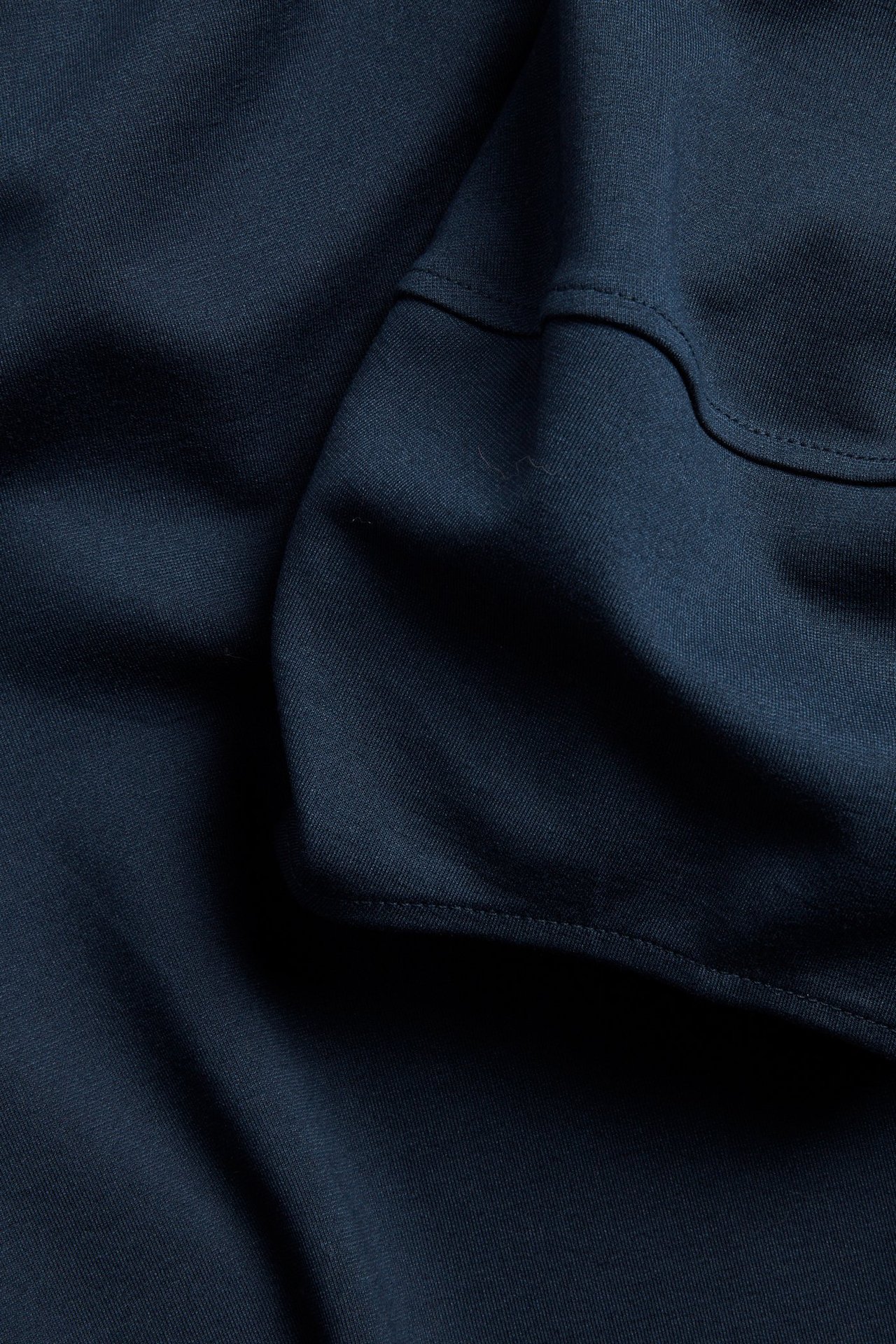 Närbild på mörkblått punto-tyg från en topp, med söm-detaljer som antyder puffärmar.