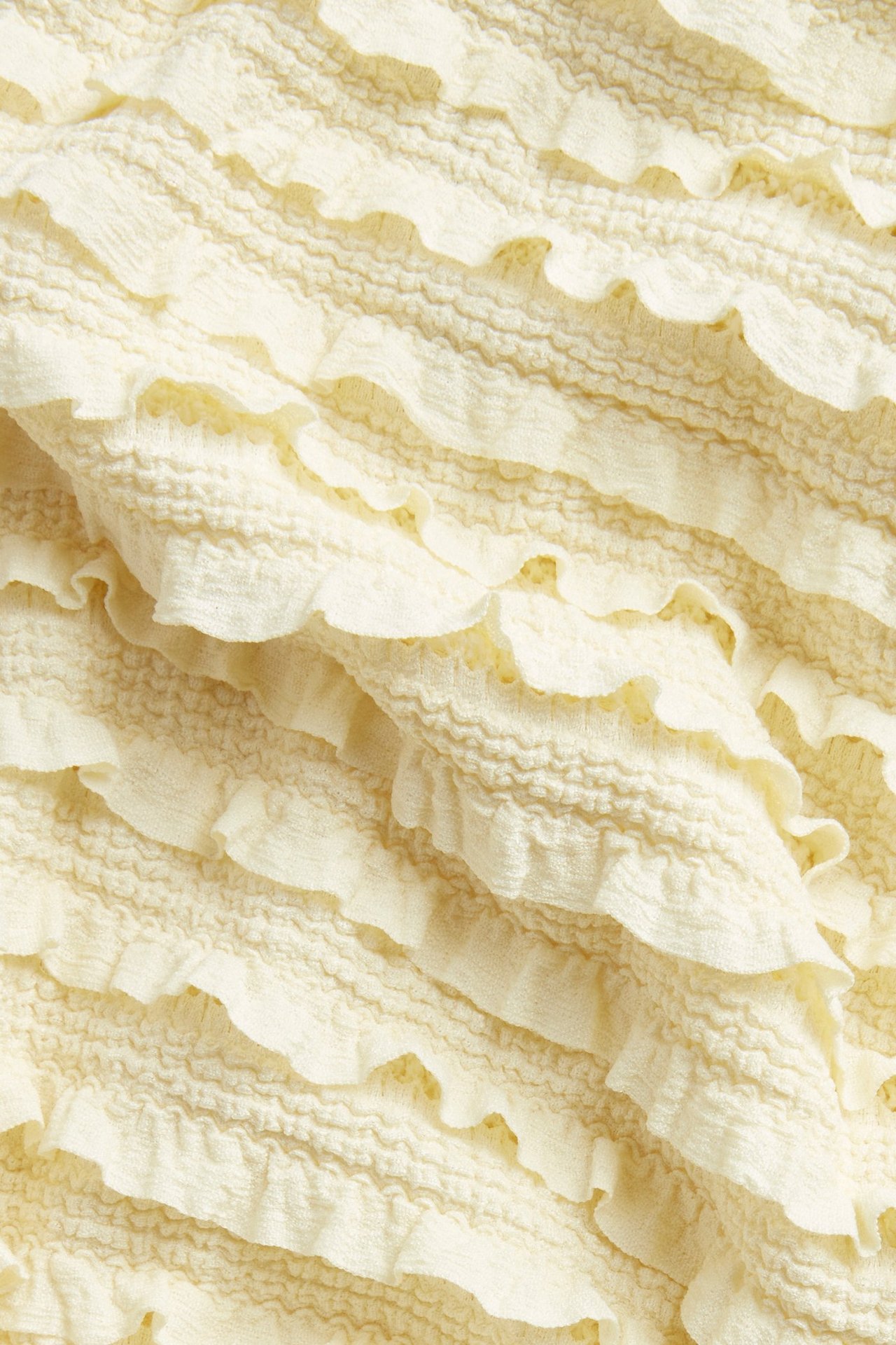 Lähikuva vaaleankeltaisesta strukturoidusta topista, jossa on vaakasuoria röyhelöitä.