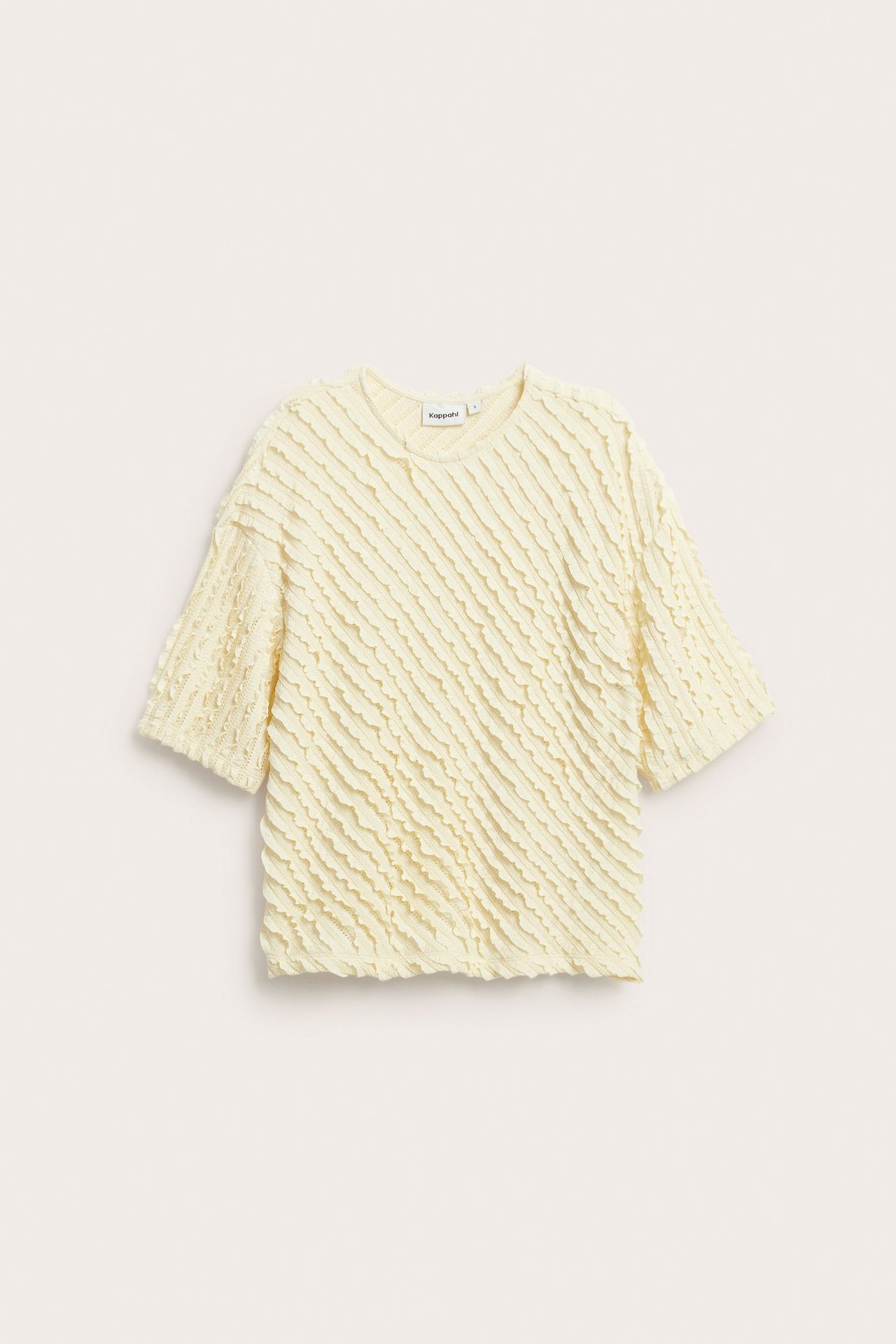 Edestä päin löysä, vaaleankeltainen lyhythihainen toppi, jossa on aaltoileva kuviointi.