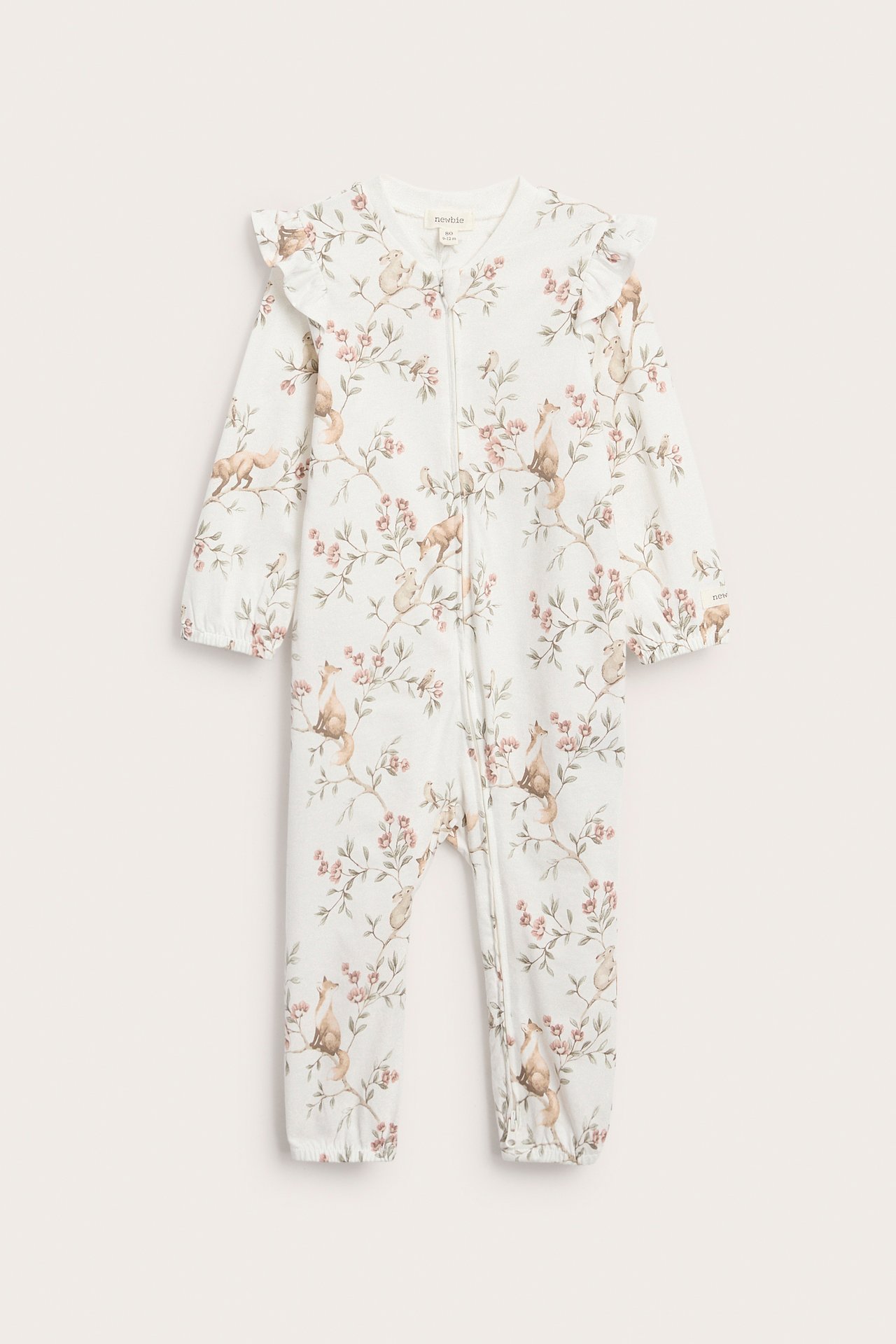Edestä: Luonnonvalkoiset puuvillavauvanpyjamat metsäeläinprintillä, röyhelöillä, joustavilla hihansuilla ja vetoketjulla.