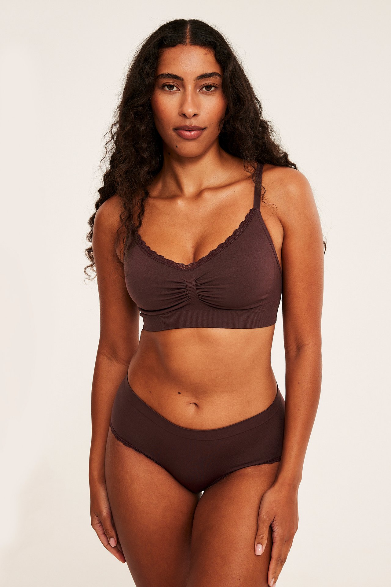 Frontvisning av en kvinne i mørkebrun blonde-BH og matchende truser.