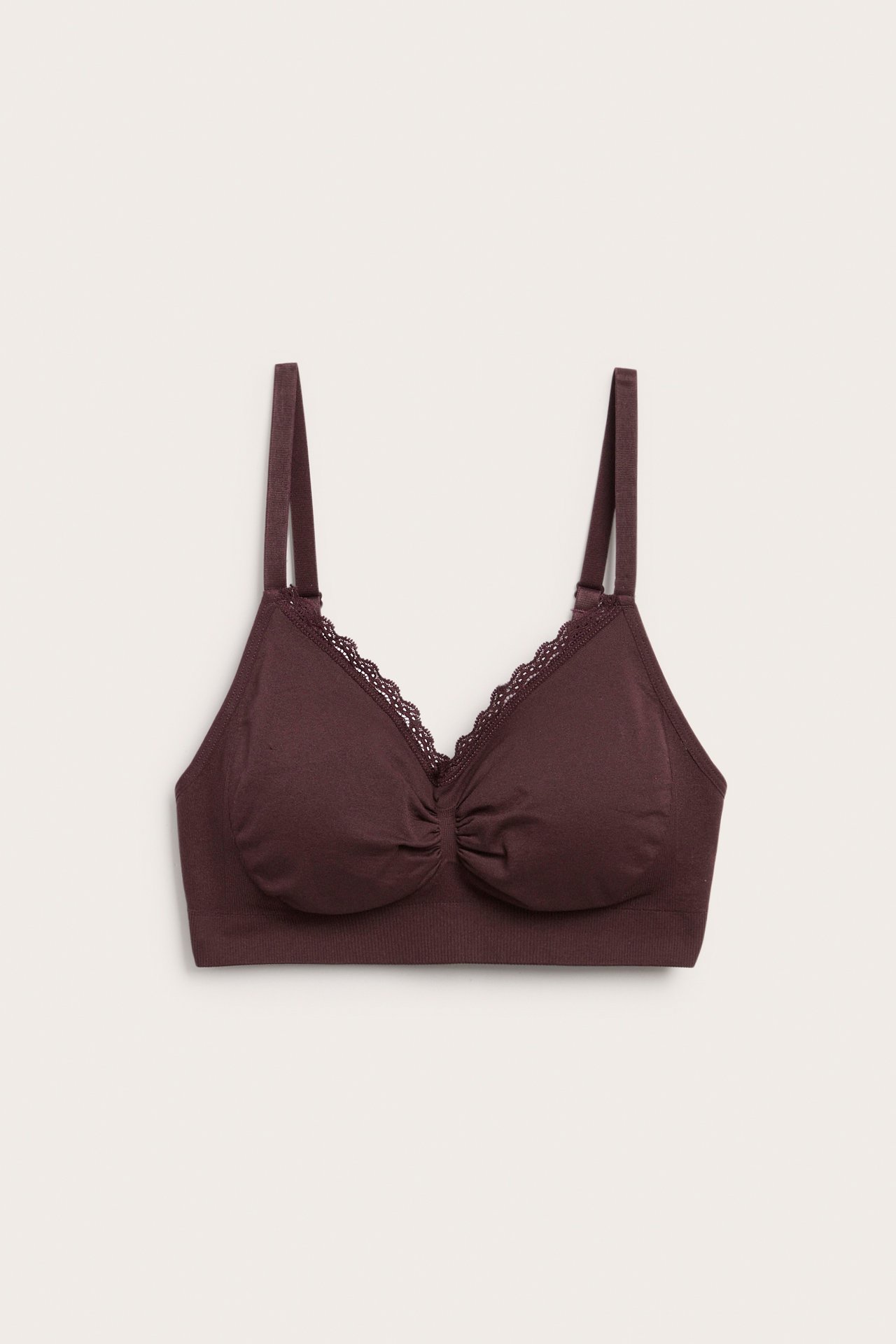 Framifrån, en mörkröd mjuk bralette med spetsdetaljer och justerbara axelband.