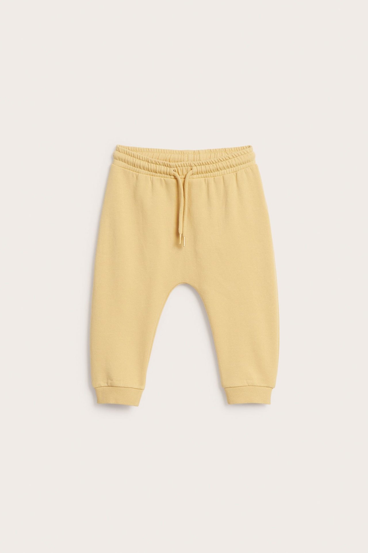 Gul baby-joggebukse med elastisk midje og snøring, forfra.