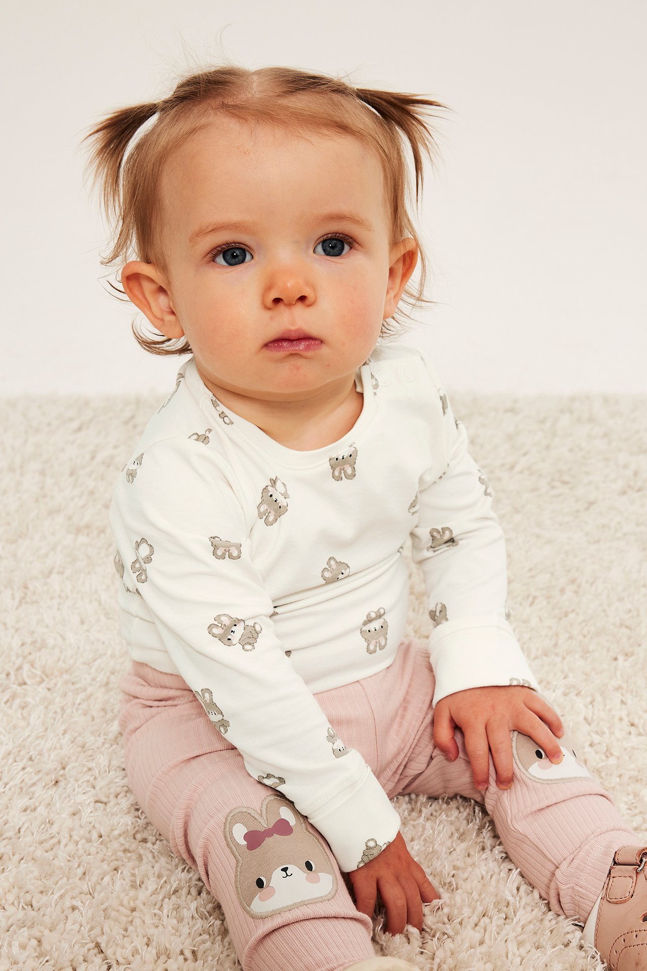 Baby sitter i rosa ribbade leggings med kaninmärken och vit långärmad kanintopp.