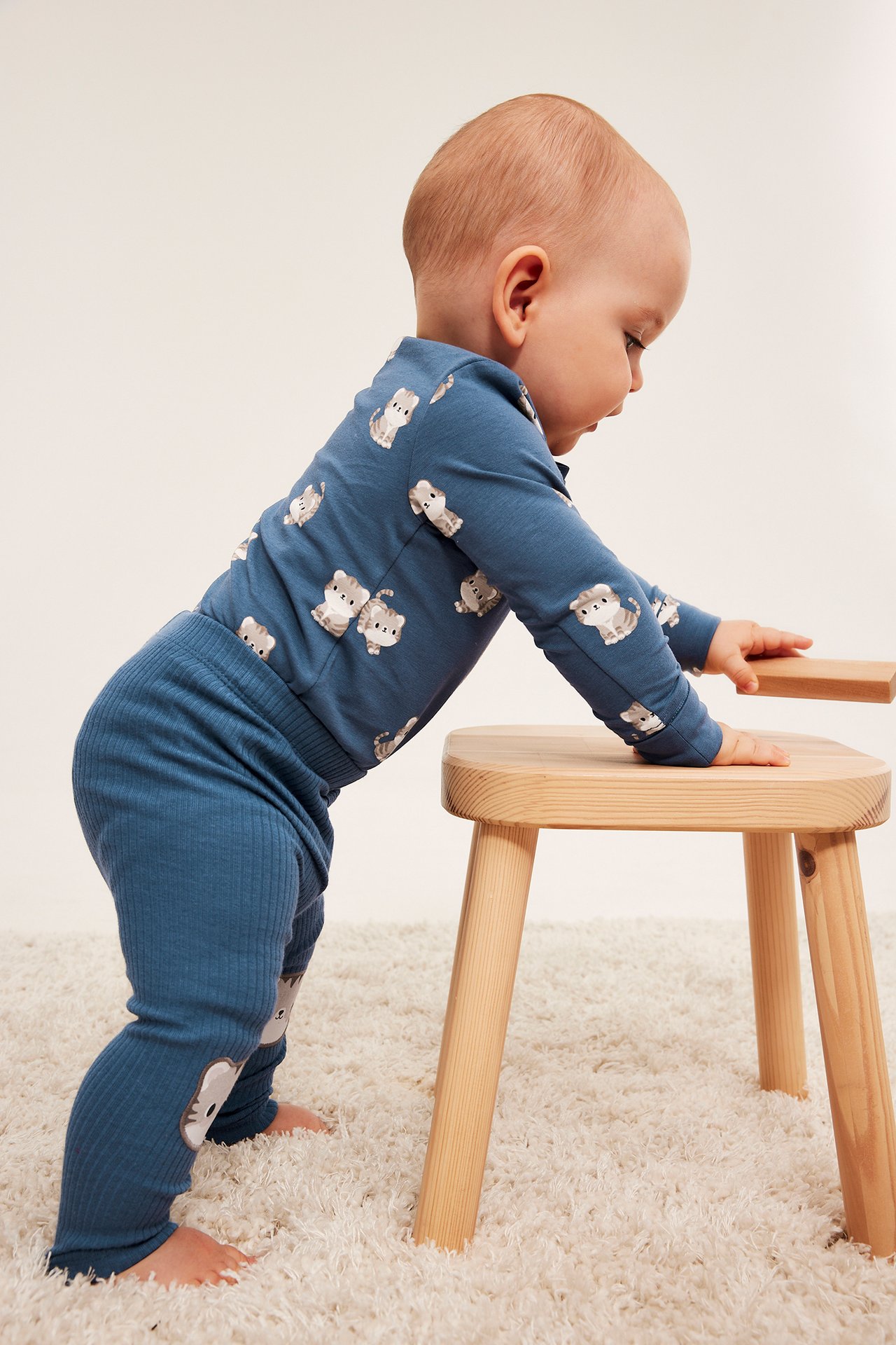 Sivukuva vauvasta, yllään sininen pitkähihainen kissaprinttipaita ja siniset ribbileggingsit.