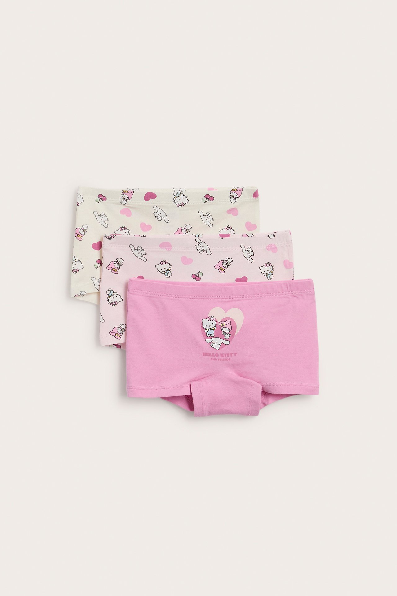 Widok z przodu trzech par dziecięcych bokserek Sanrio: różowe, jasnoróżowe i kremowe z nadrukami postaci.