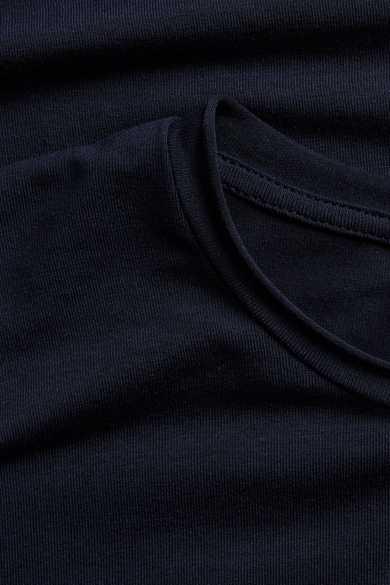 Zbliżenie na granatowy t-shirt z prążkowanej dzianiny z okrągłym dekoltem.