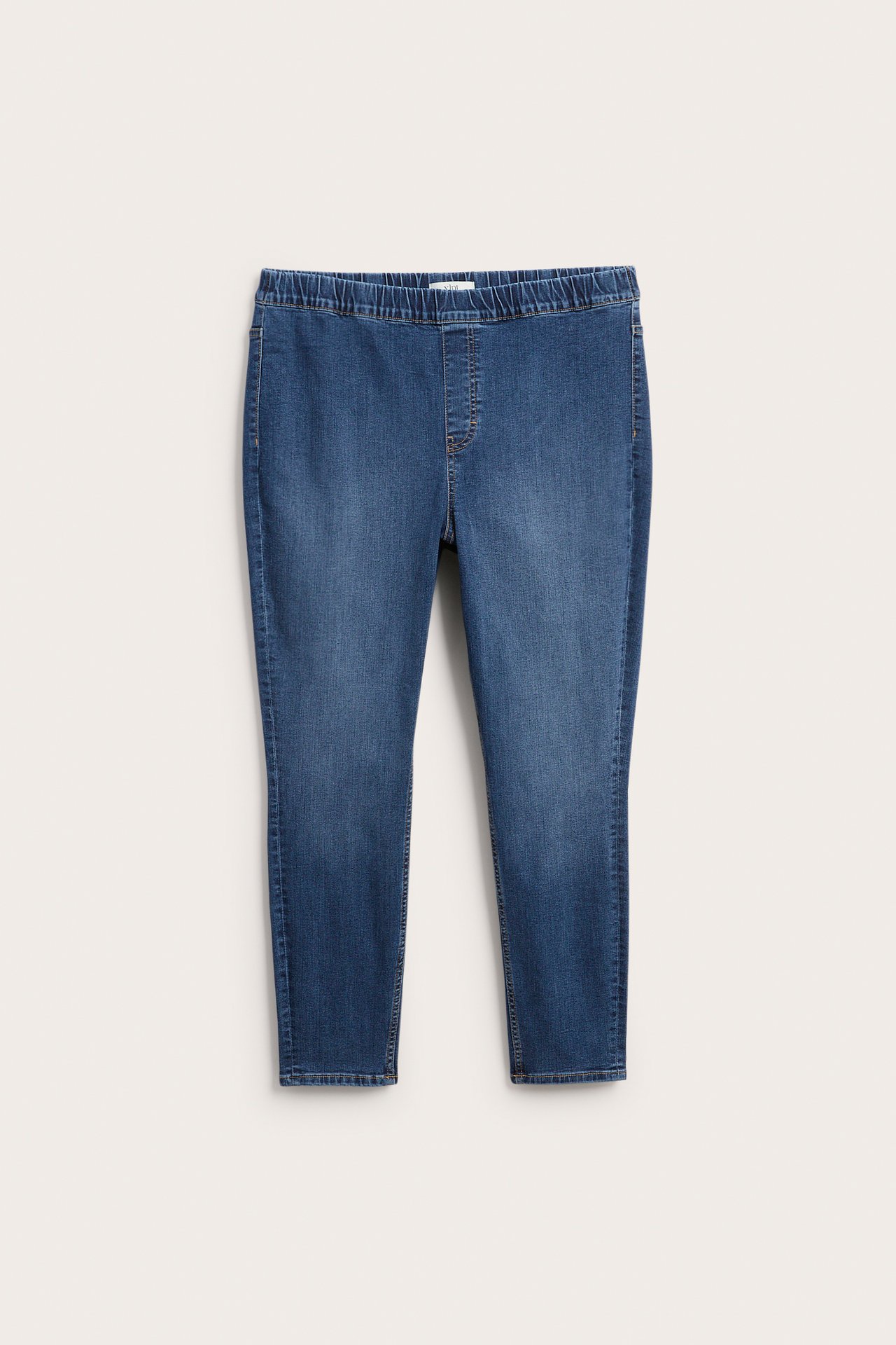 Frontvisning av et par blå denim-jeggings med elastisk linning.