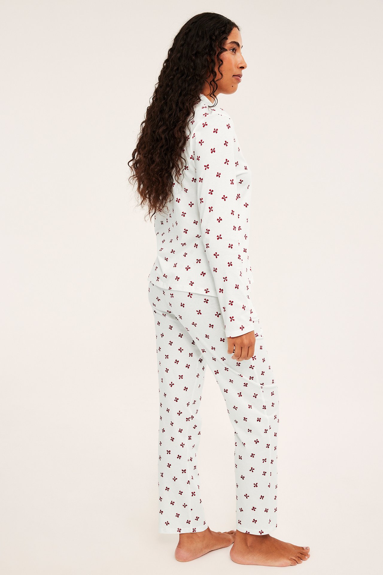 Sivukuva naisesta vaaleansinisessä pyjamassa, jossa punainen kukkakuvio.