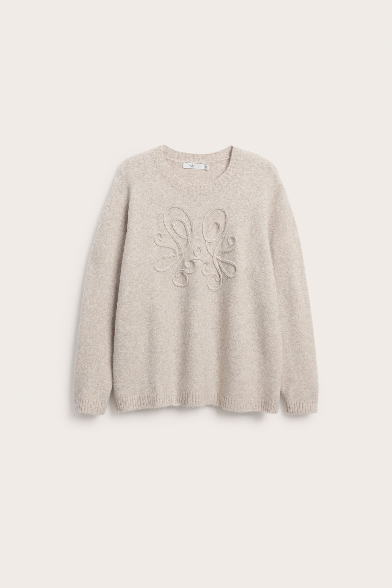Frontbilde av en beige langermet genser med brodert design.