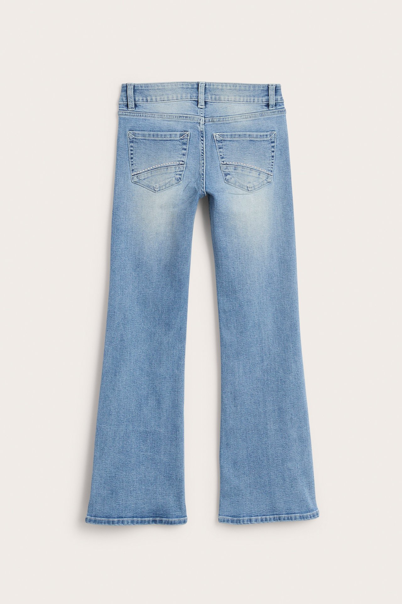 Bakifrån av ljusblå jeans med utsvängda ben och dekorerade bakfickor.