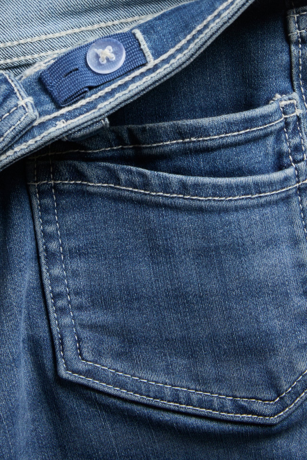 Lähikuva lasten sinisistä denimbootcut-farkuista, joissa etutasku ja säädettävä joustovyötärö.