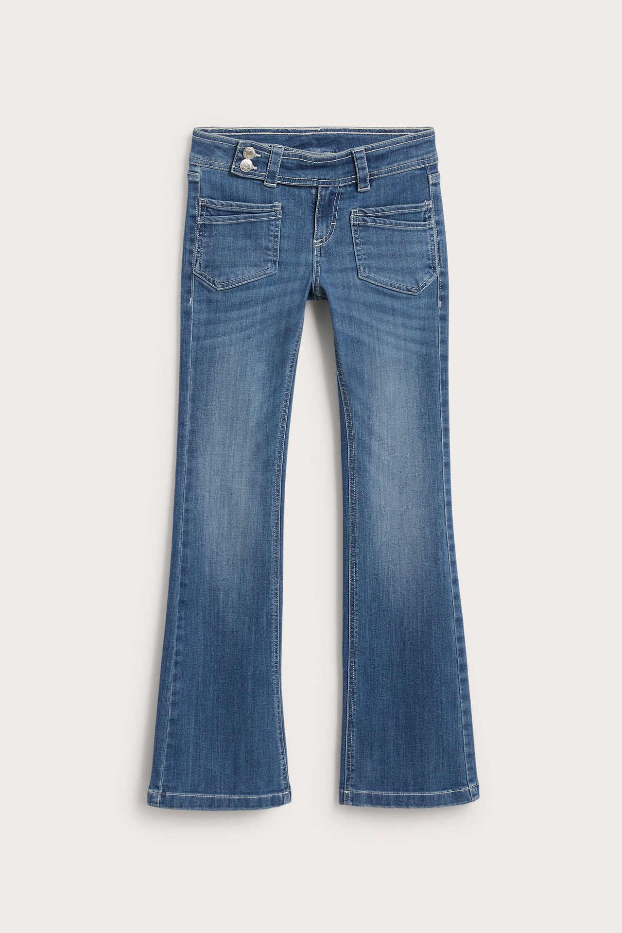Edestä näkymä lasten sinisistä denim low waist bootcut farkuista etutaskuilla ja nappikiinnityksellä.