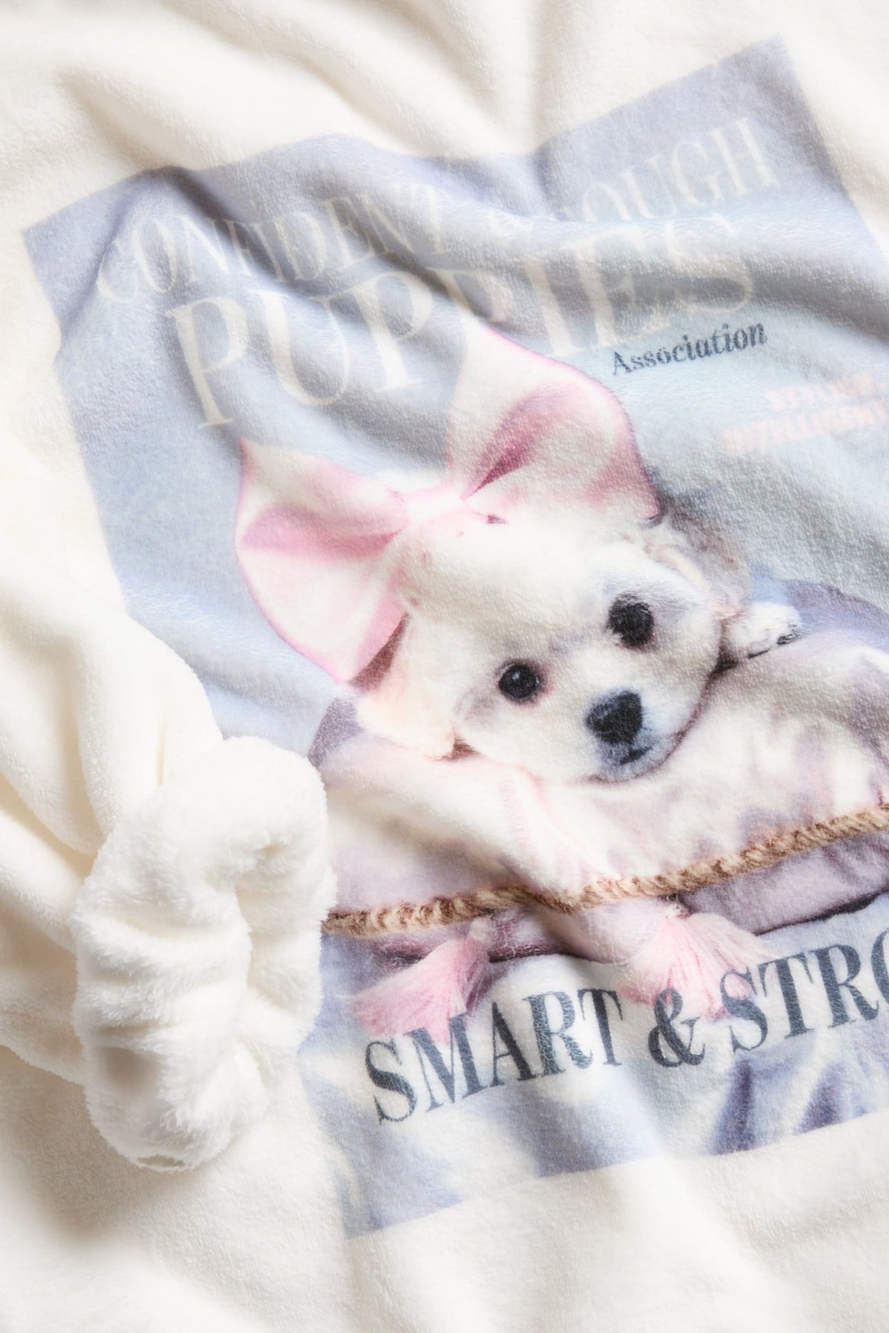 Zbliżenie na off-white polarową bluzę dziecięcą z dużym nadrukiem szczeniaka z przodu.