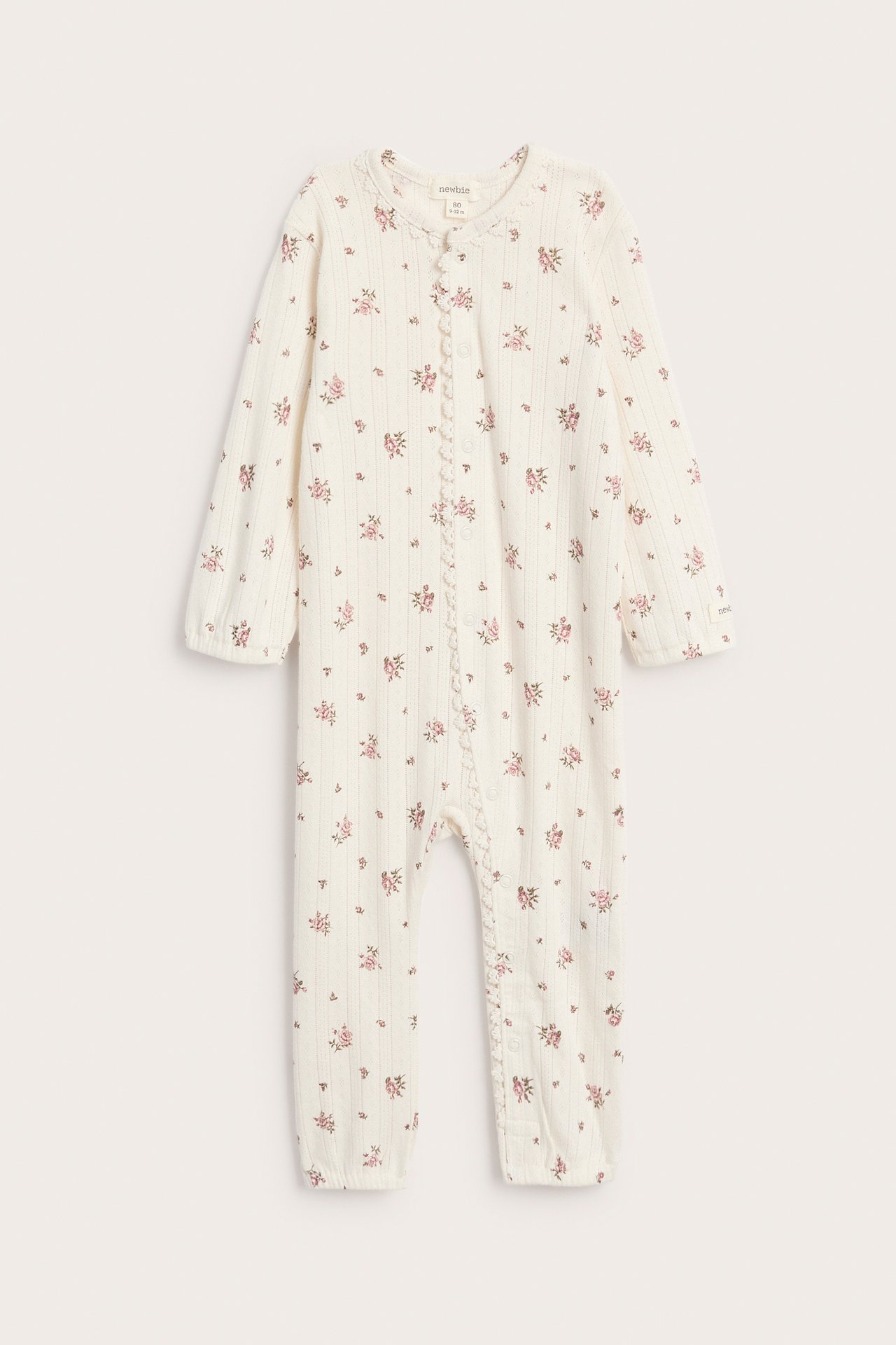 Framsida av en baby off-white ribbad sparkdräkt med rosa blommigt mönster och tryckknappar.