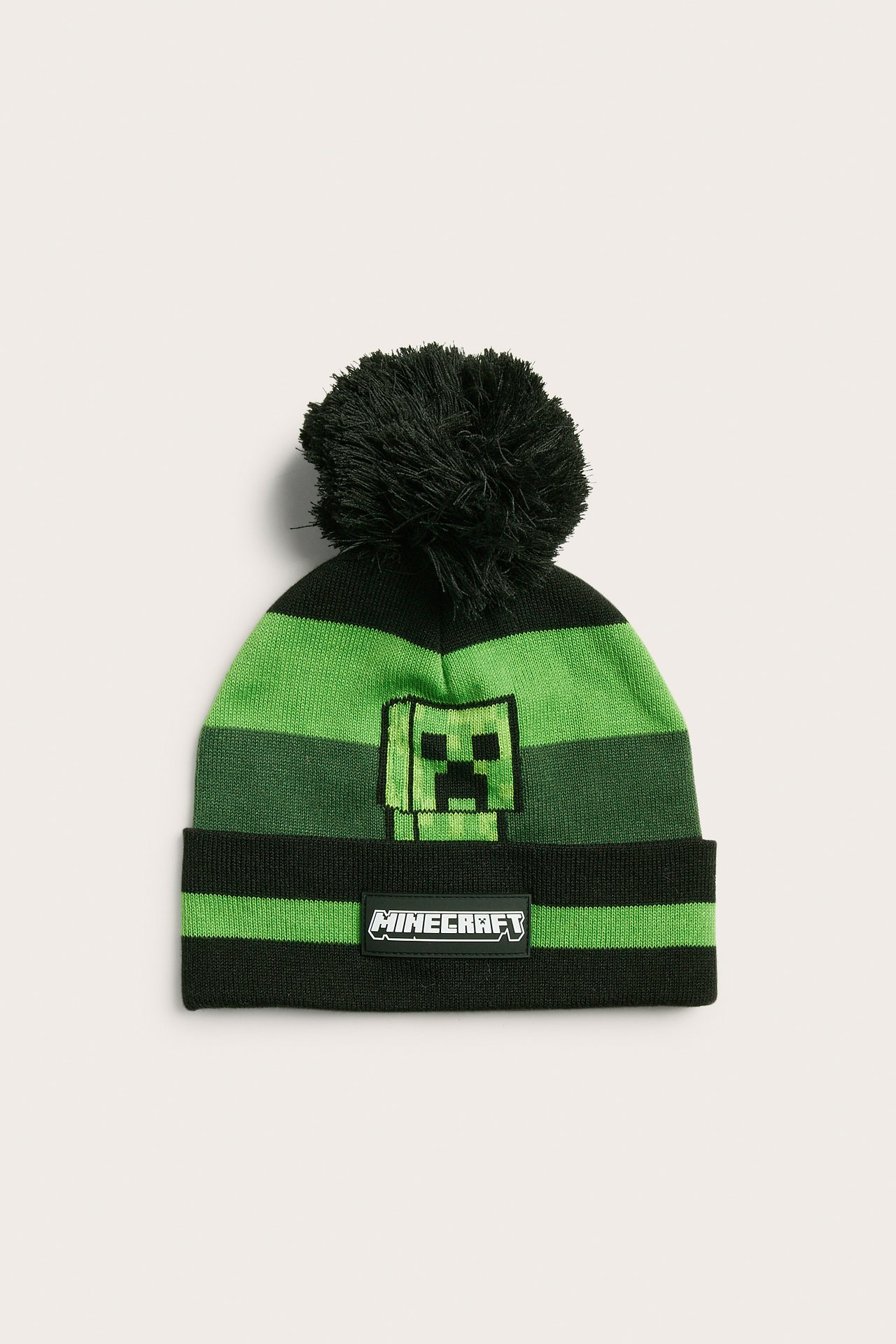 Frontalvisning av en stripete svart og grønn Minecraft-lue med Creeper-design og dusk.