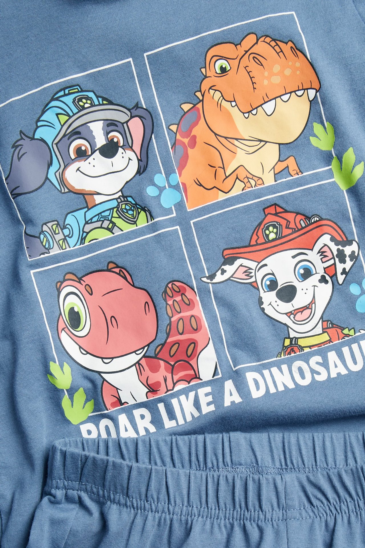 Lähikuva sinisistä lasten puuvillapyjamista, joissa Ryhmä Hau Dino -printti ja joustava vyötärö.