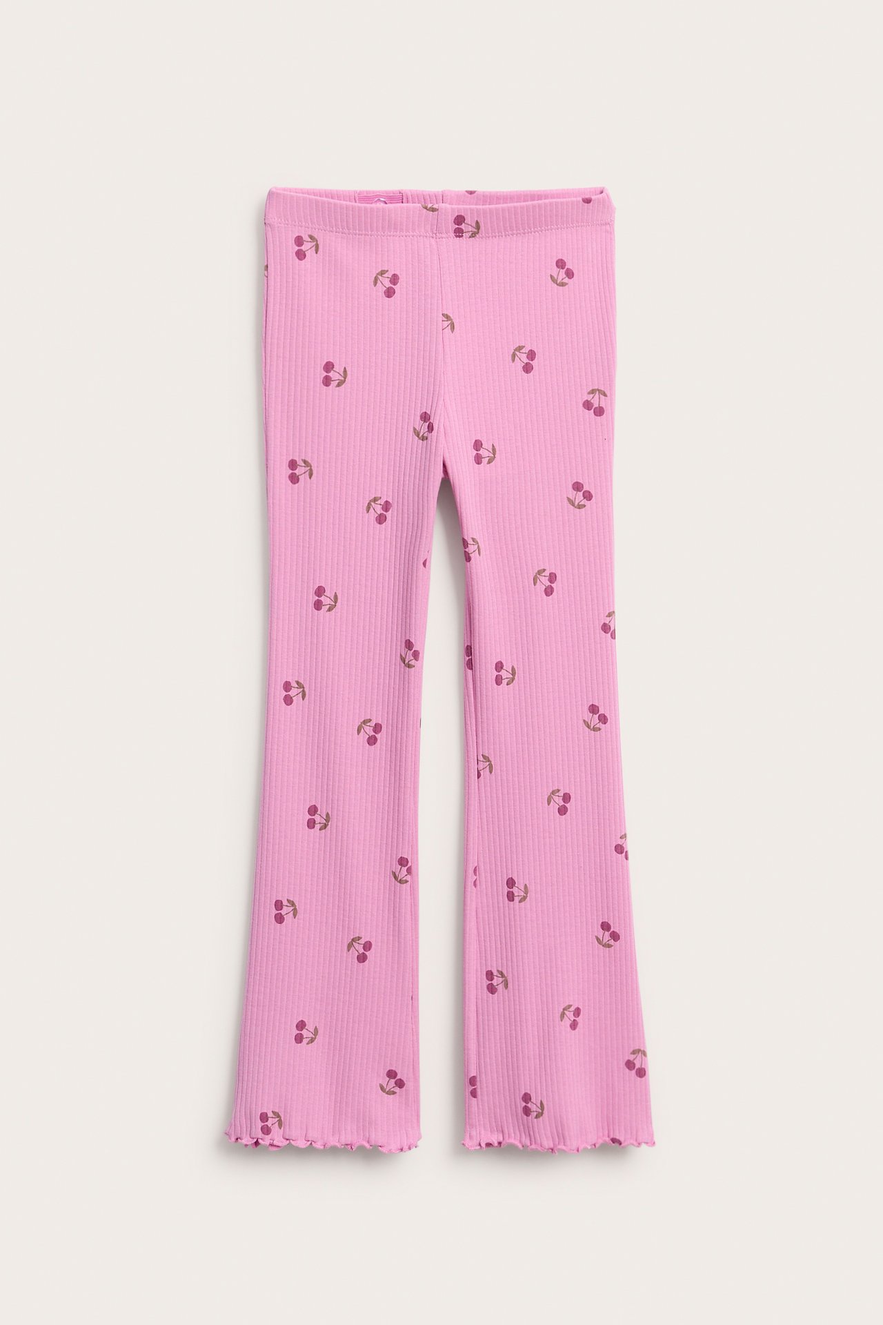 Framsida av barnens rosa ribbade utsvängda byxor med körsbärstryck och resårlinning.