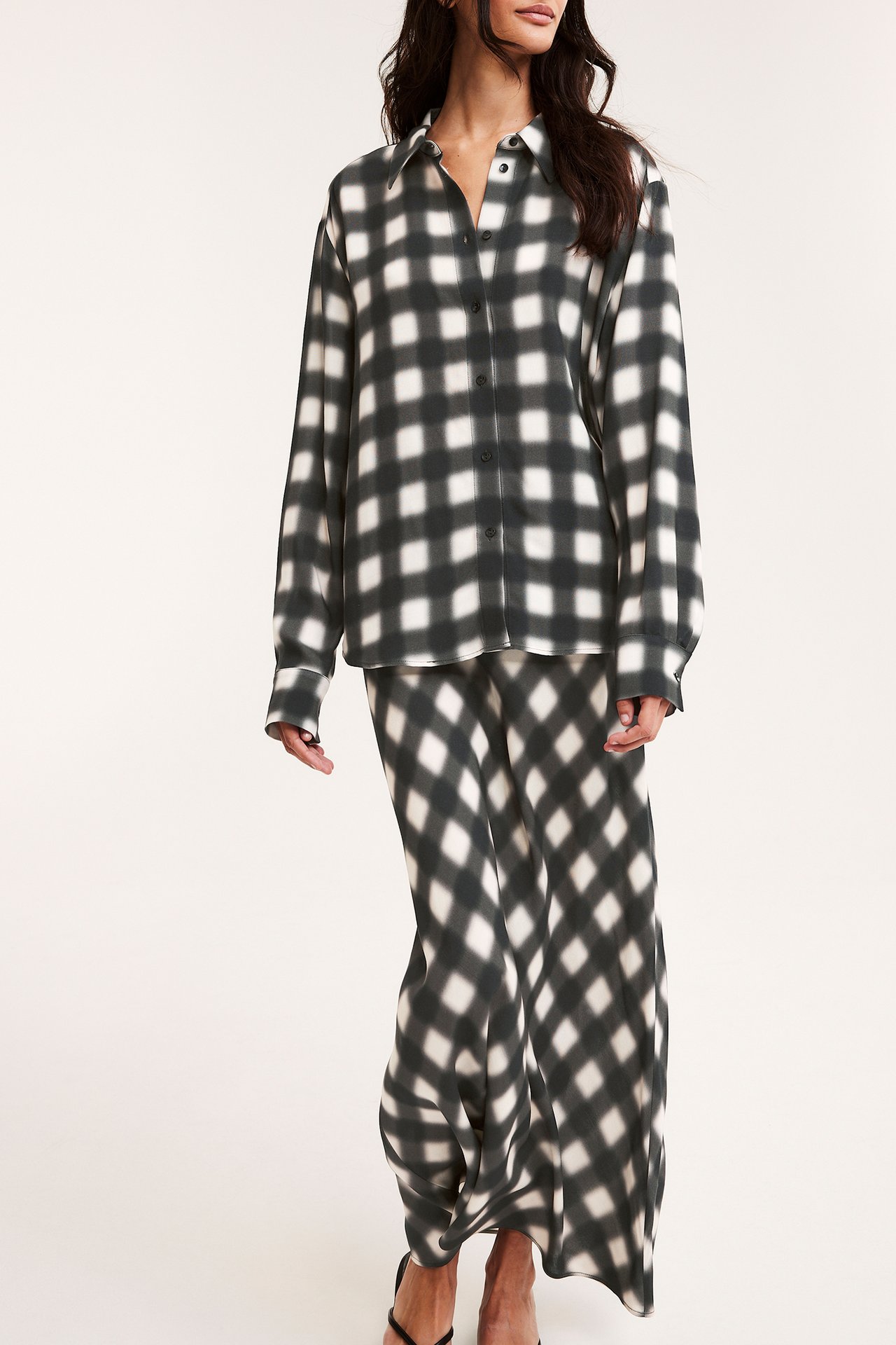 Front view: kvinna i svart och benvit rutig viskos långkjol och matchande knäppt skjorta.