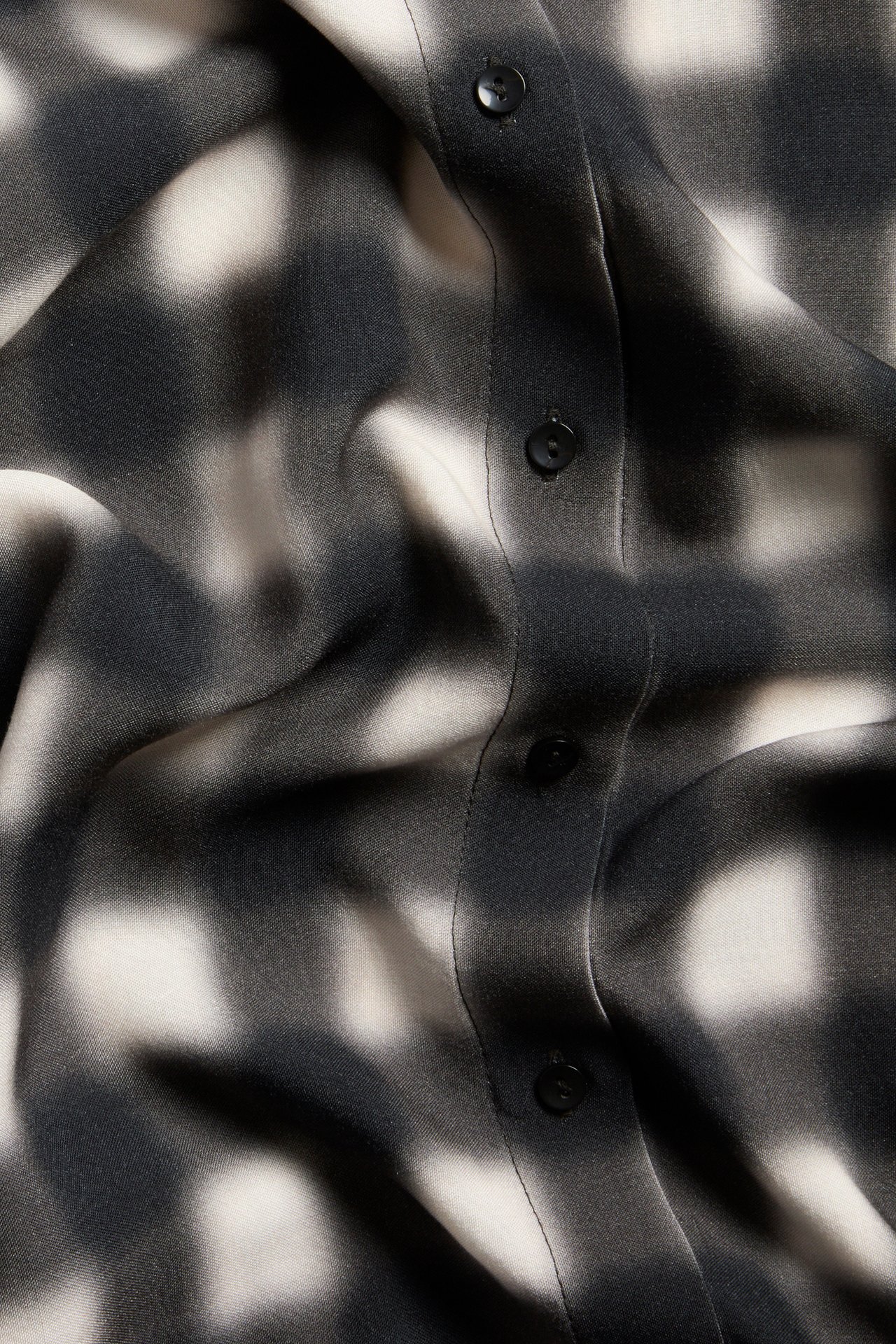 Närbild av svart och vitrutig viskosskjorta med synlig knappslå.