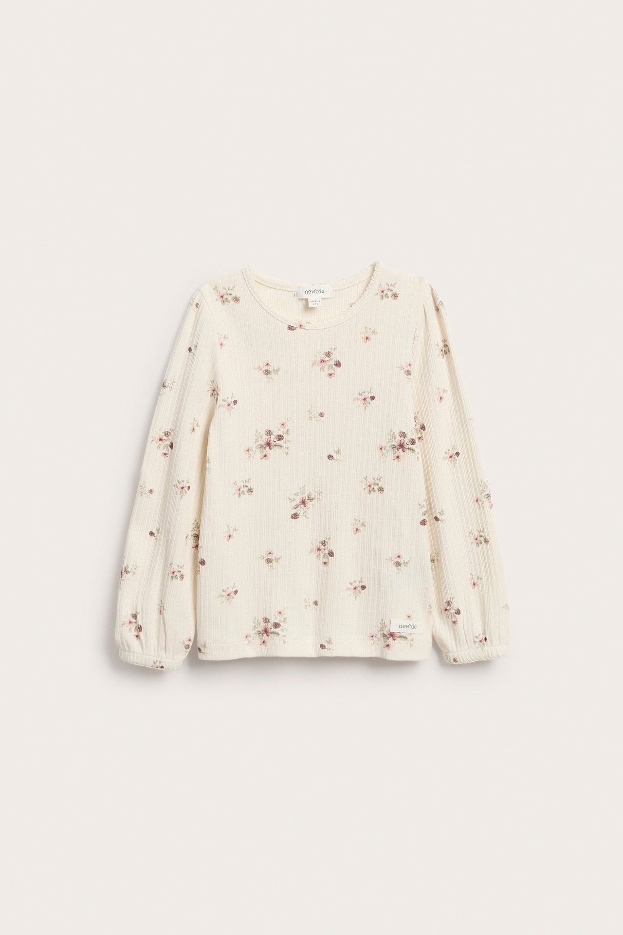 Front, en kremfarget ribbet langermet barnegenser med blomstermønster.