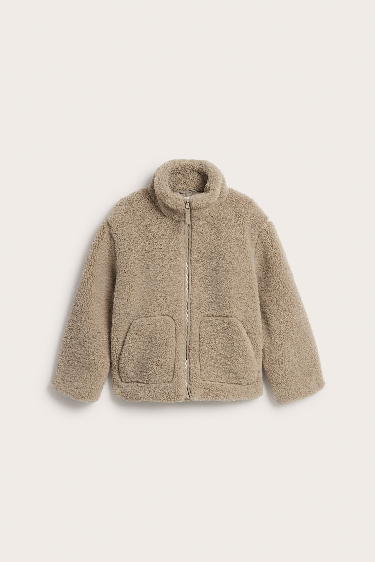 Framifrån, barns beige fluffig hel dragkedja jacka med två fickor.
