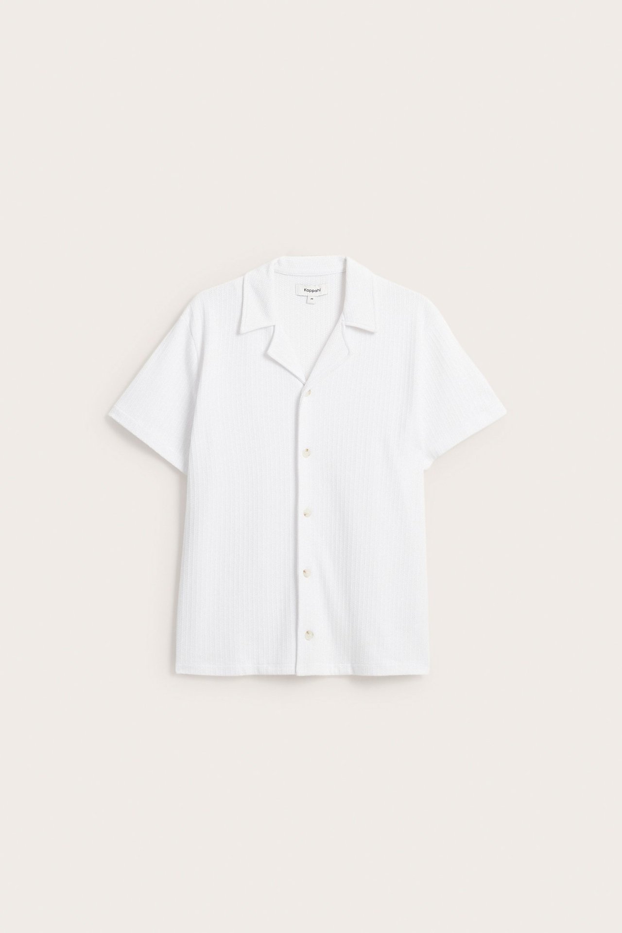 Framifrån: Vit kortärmad pointelle pikétröja i jersey med resortkrage och knappar fram.