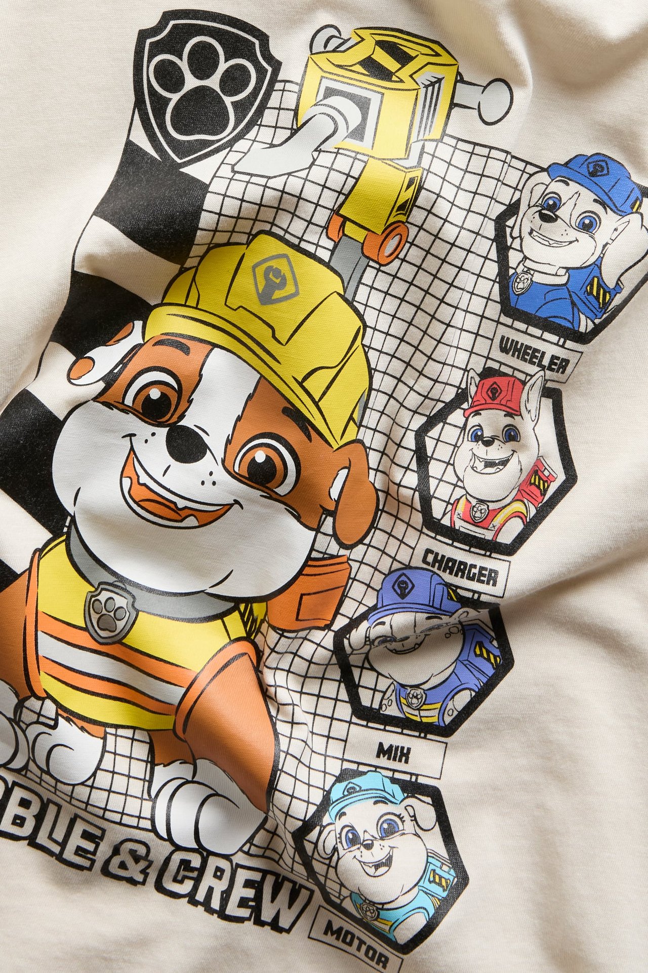 Zbliżenie na kremowy t-shirt z kolorowym nadrukiem postaci Psi Patrol 'Rubble & Crew'.