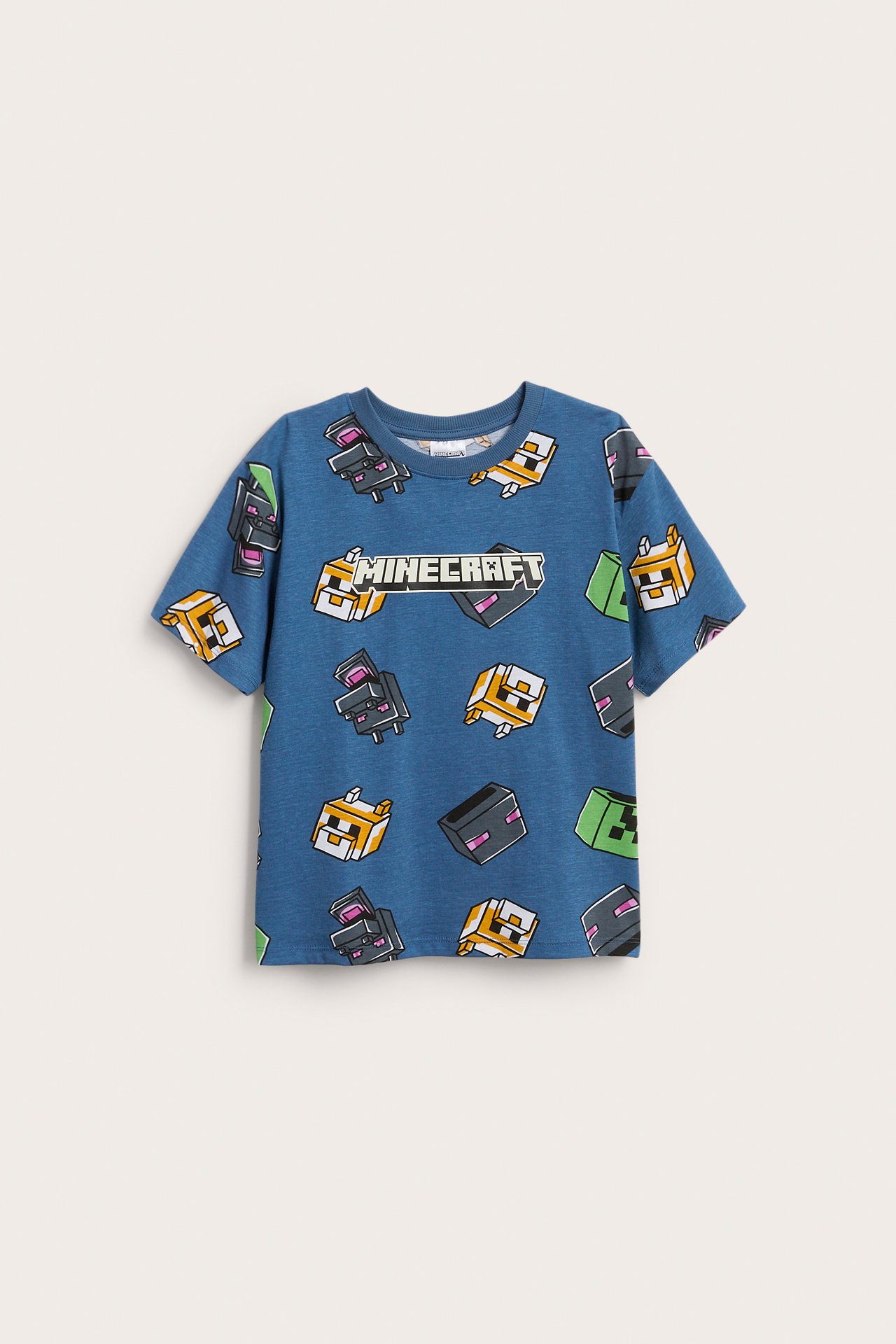 Framsida av en blå kortärmad t-shirt för barn med ett heltäckande Minecraft-mönster.