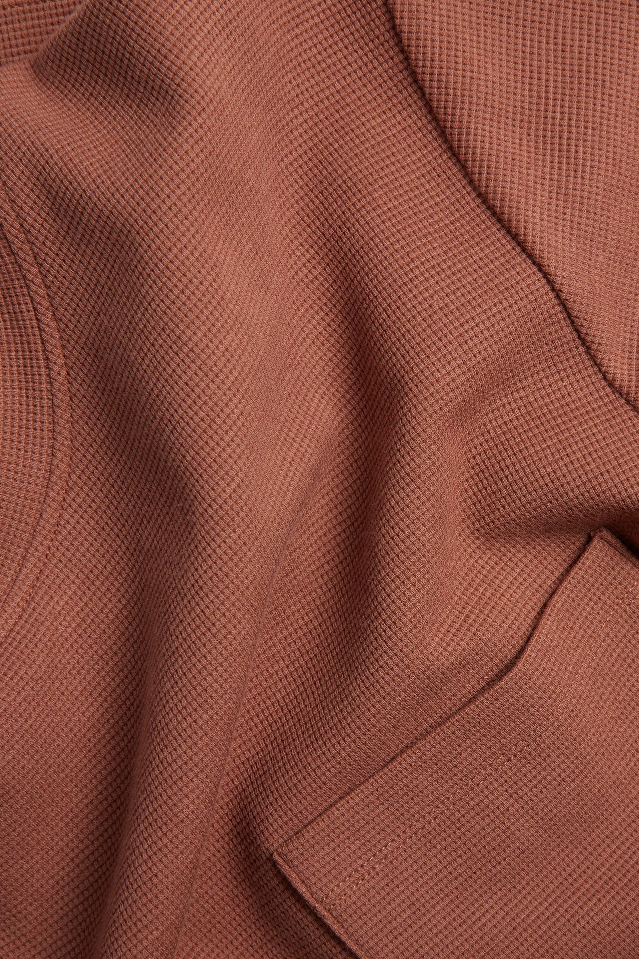 Nærbilde av en brun regular fit T-skjorte med vaffelmønster og brystlomme.