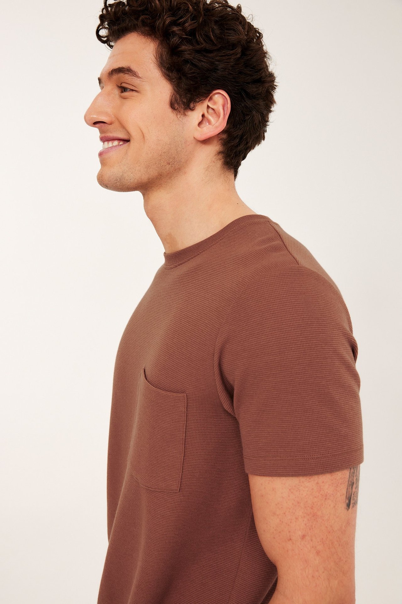 Sidevisning av mann i brun, regular fit strukturert rundhalset T-skjorte med brystlomme.