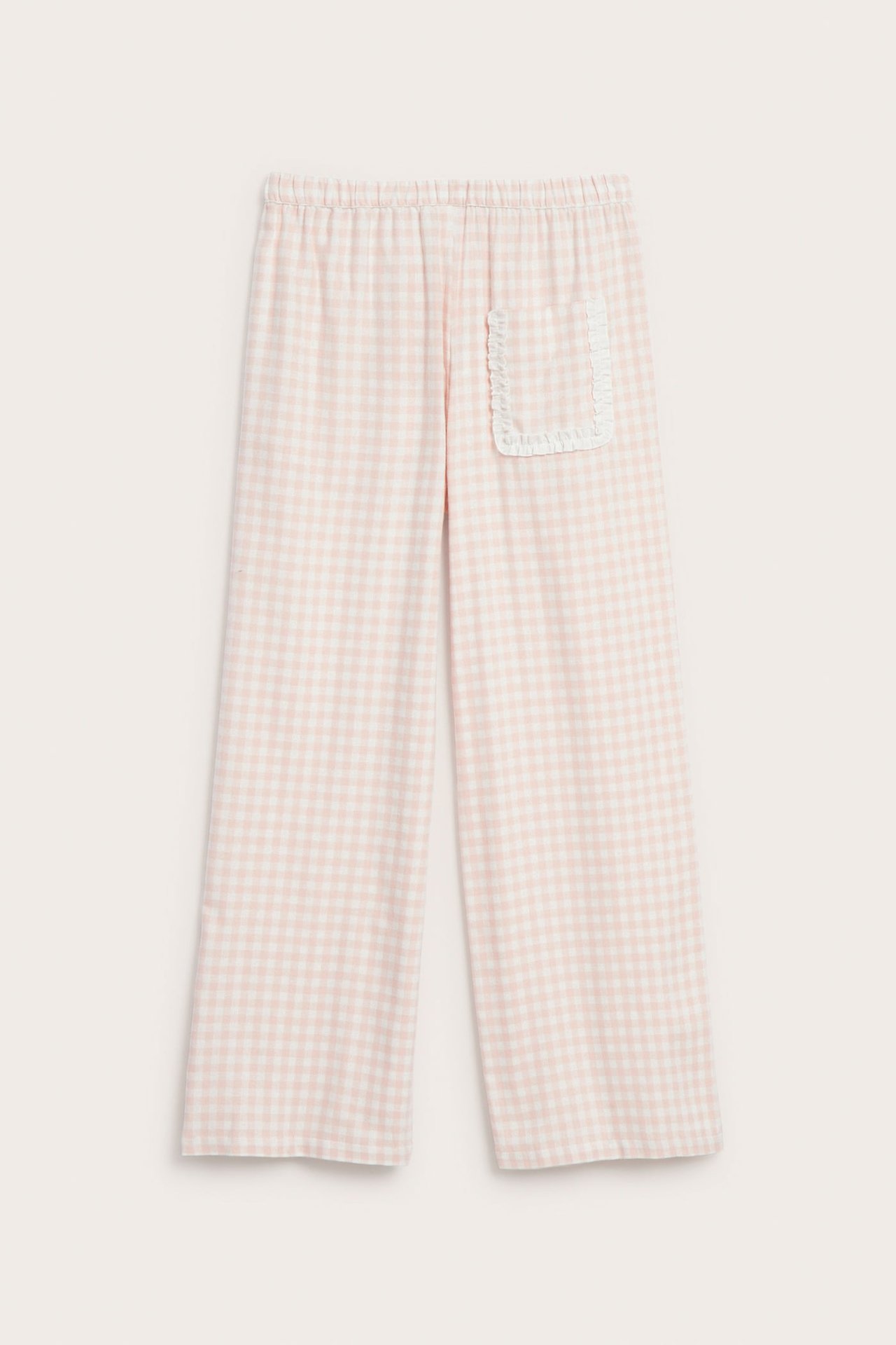 Edestä näkymä vaaleanpunaisista ja valkoisista ruudullisista pyjamahousuista, joissa on röyhelötasku.