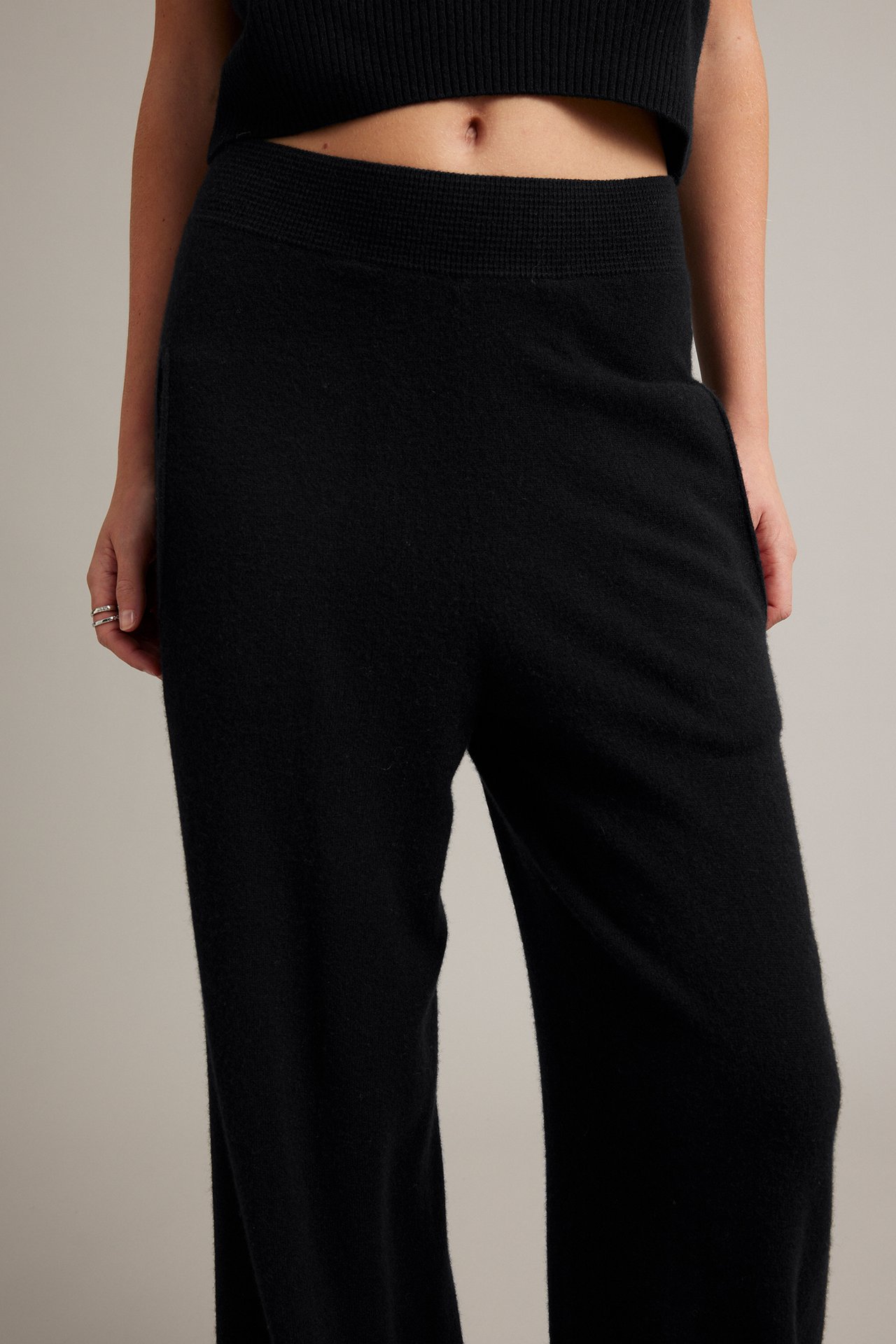 Nærbilde av svarte strikkede bukser med ribbet midje og en svart strikket crop top.