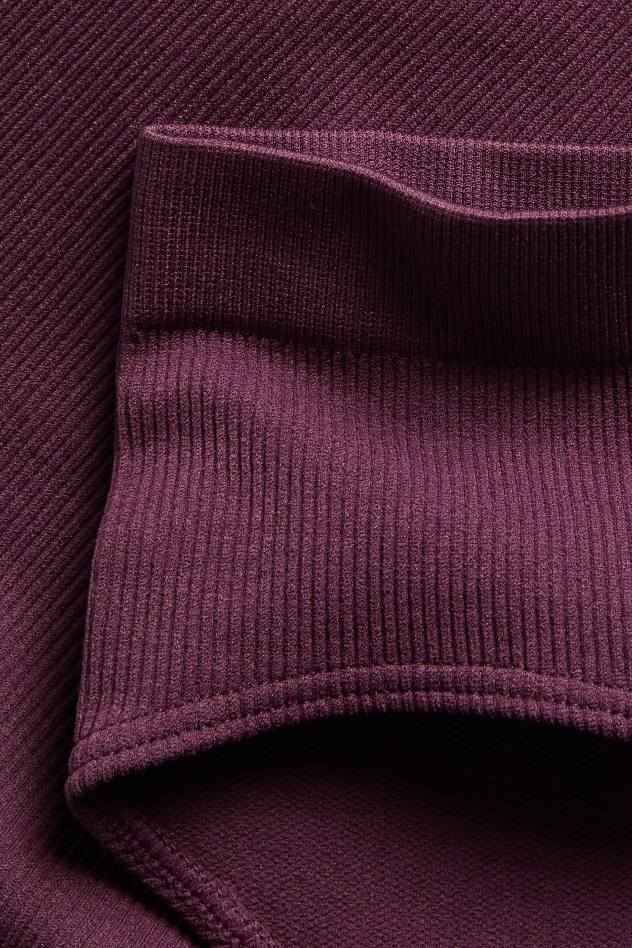 Närbild på vinröda sömlösa ribbade hipstertrosor, som visar resårmidjan och ribbad textur.