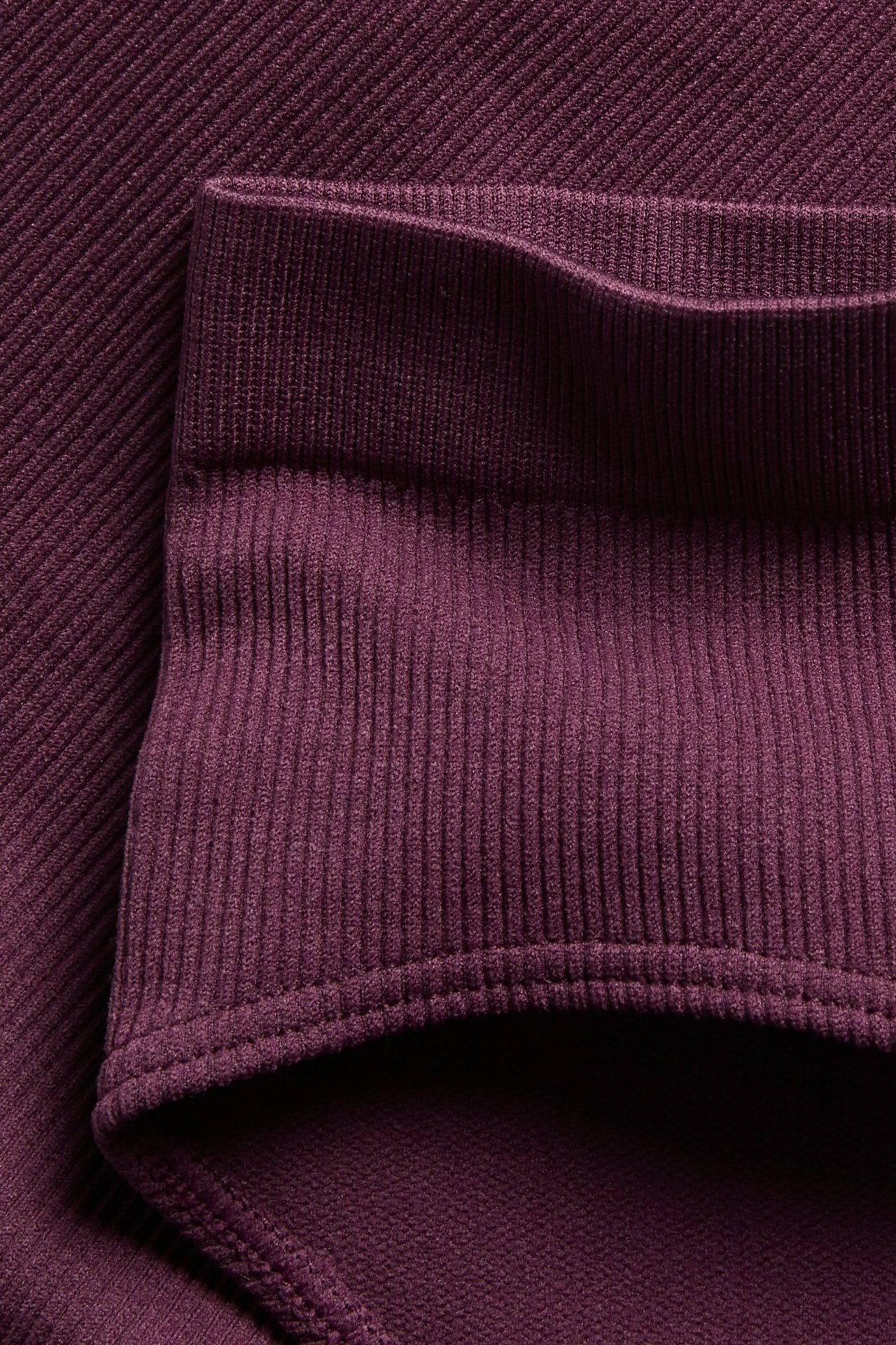 Nærbilde av vinrøde sømløse ribbestrikkede hipster truser, som viser elastisk linning og ribbet tekstur.