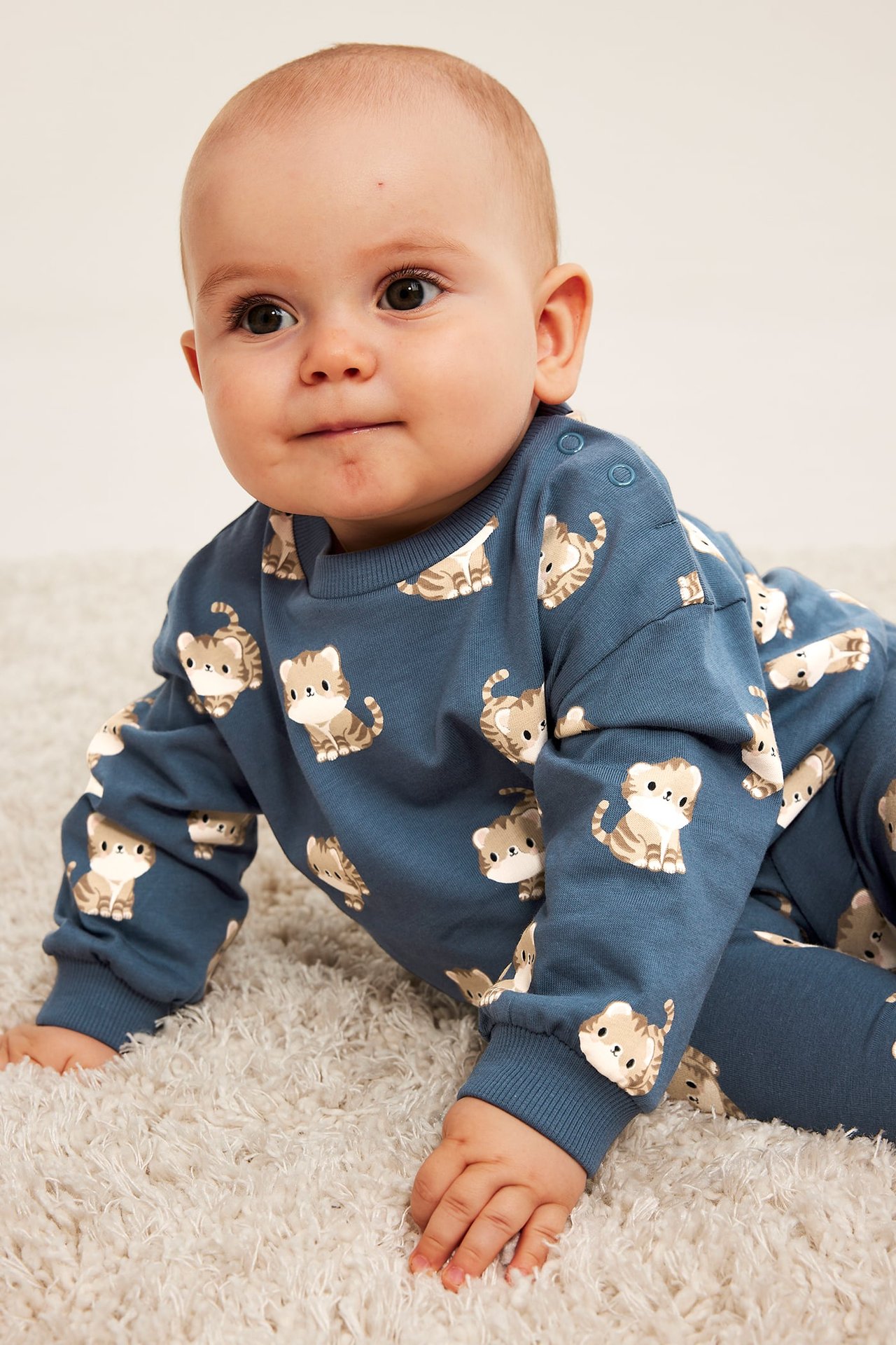Närbild på ett babyklädeset i blått med långärmad tröja och byxor med kattmönster.