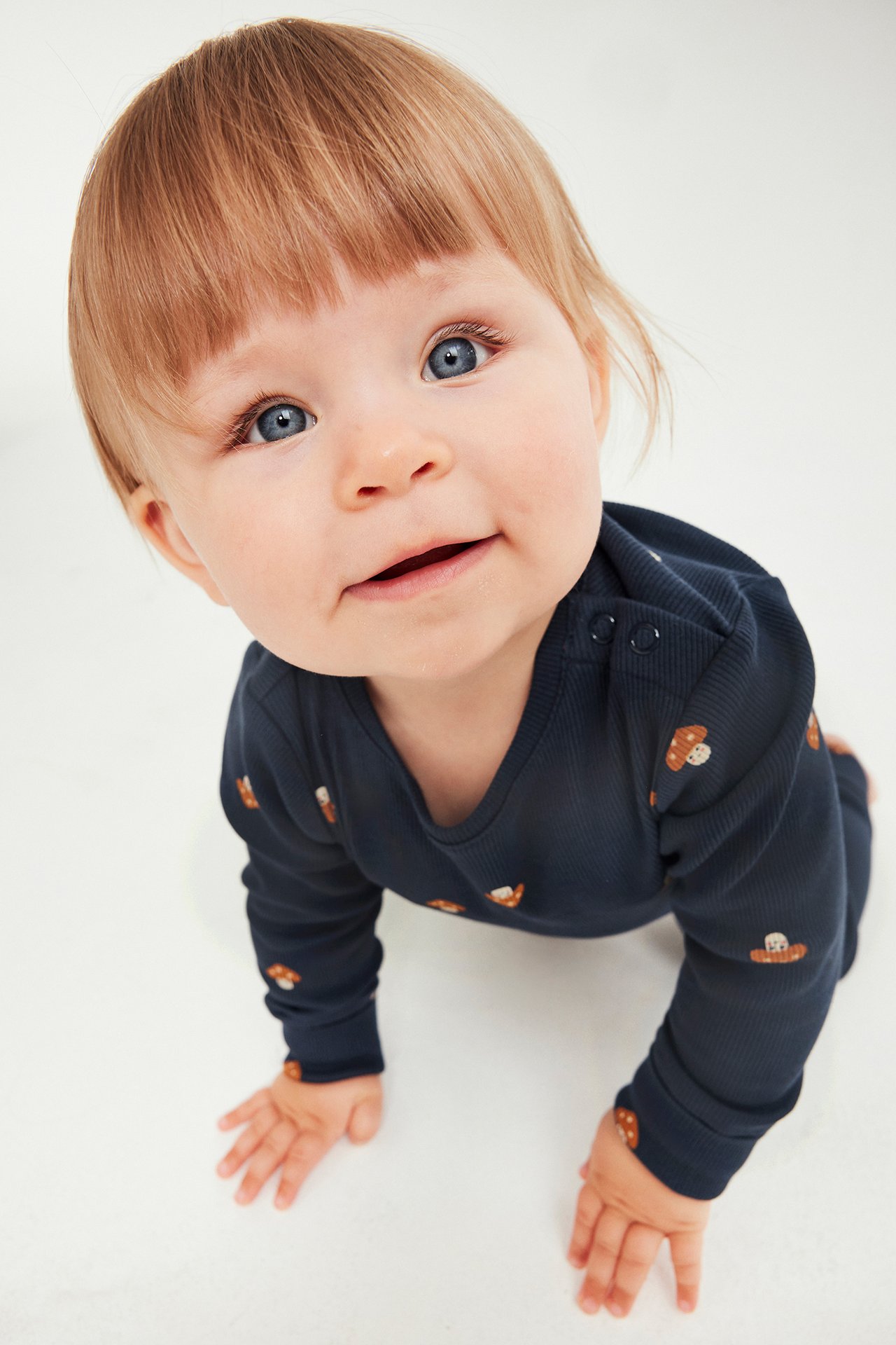 Framsida av baby i mörkblå ribbad långärmad body med svamptryck och tryckknappar.