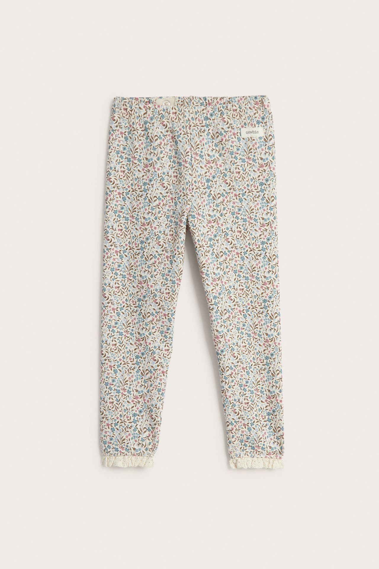 Edestäpäin vauvan beiget kukalliset leggingsit röyhelöpitseillä.