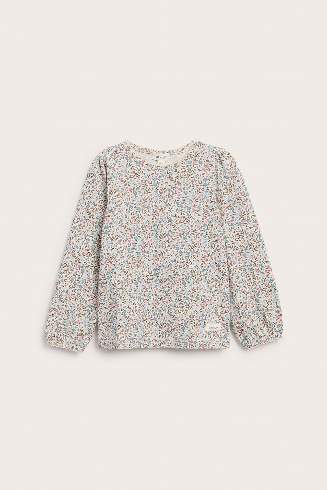 Framsida av en barnlångärmad topp i benvitt med färgglatt blommönster.