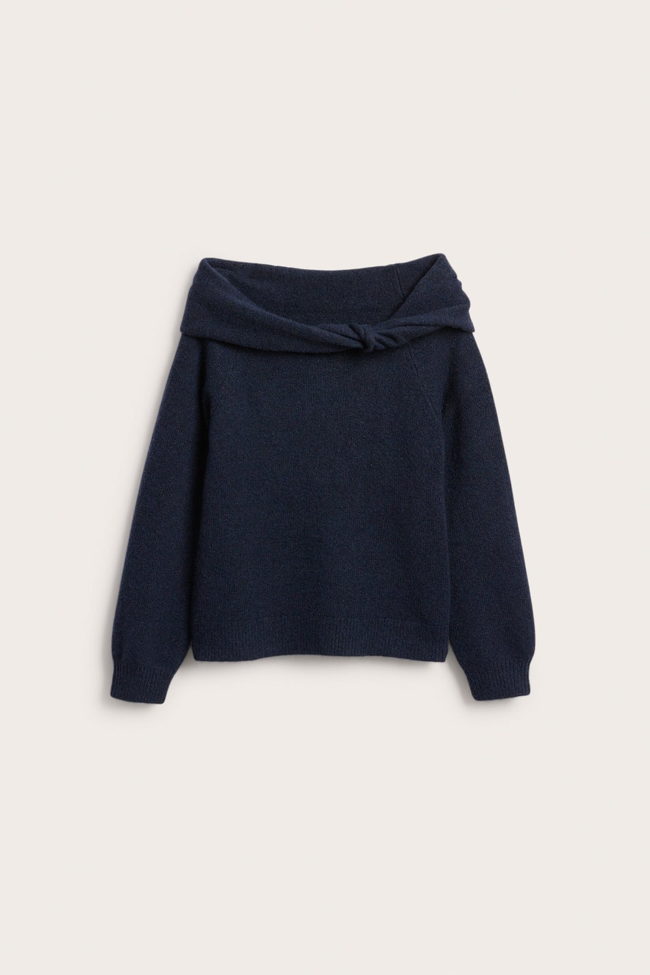 Edestä kuvattuna tummansininen off-shoulder-neule, jossa solmuyksityiskohta pääntiessä.