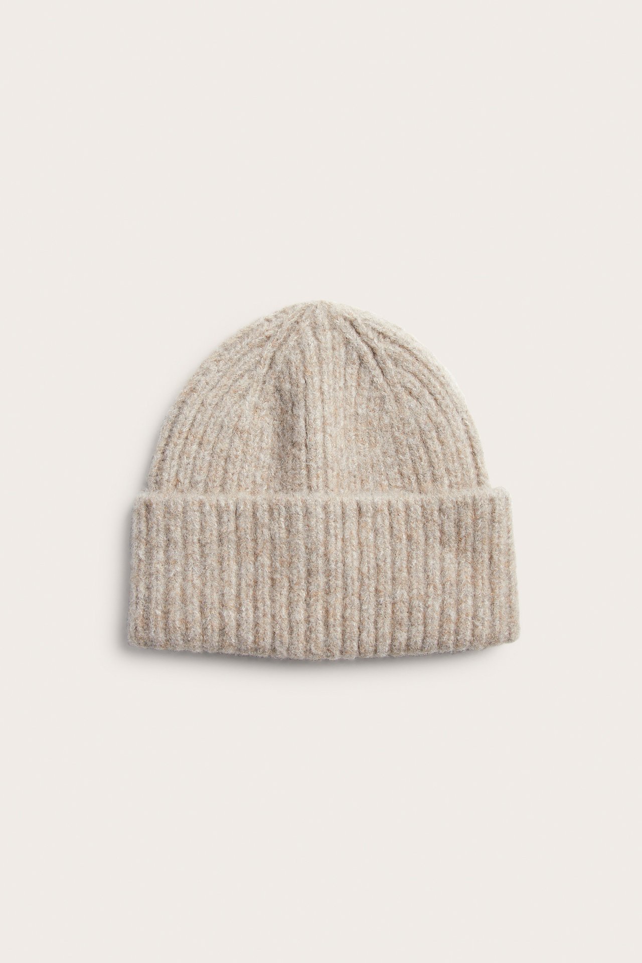 Front av en lys beige ribbestrikket lue med brettet kant.